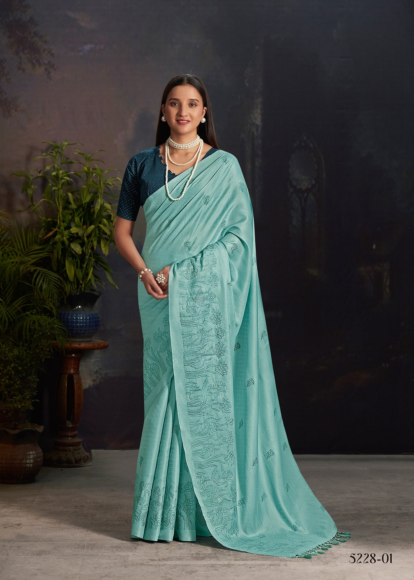 Teal silk saree with embroidered motifs and draped pallu detail