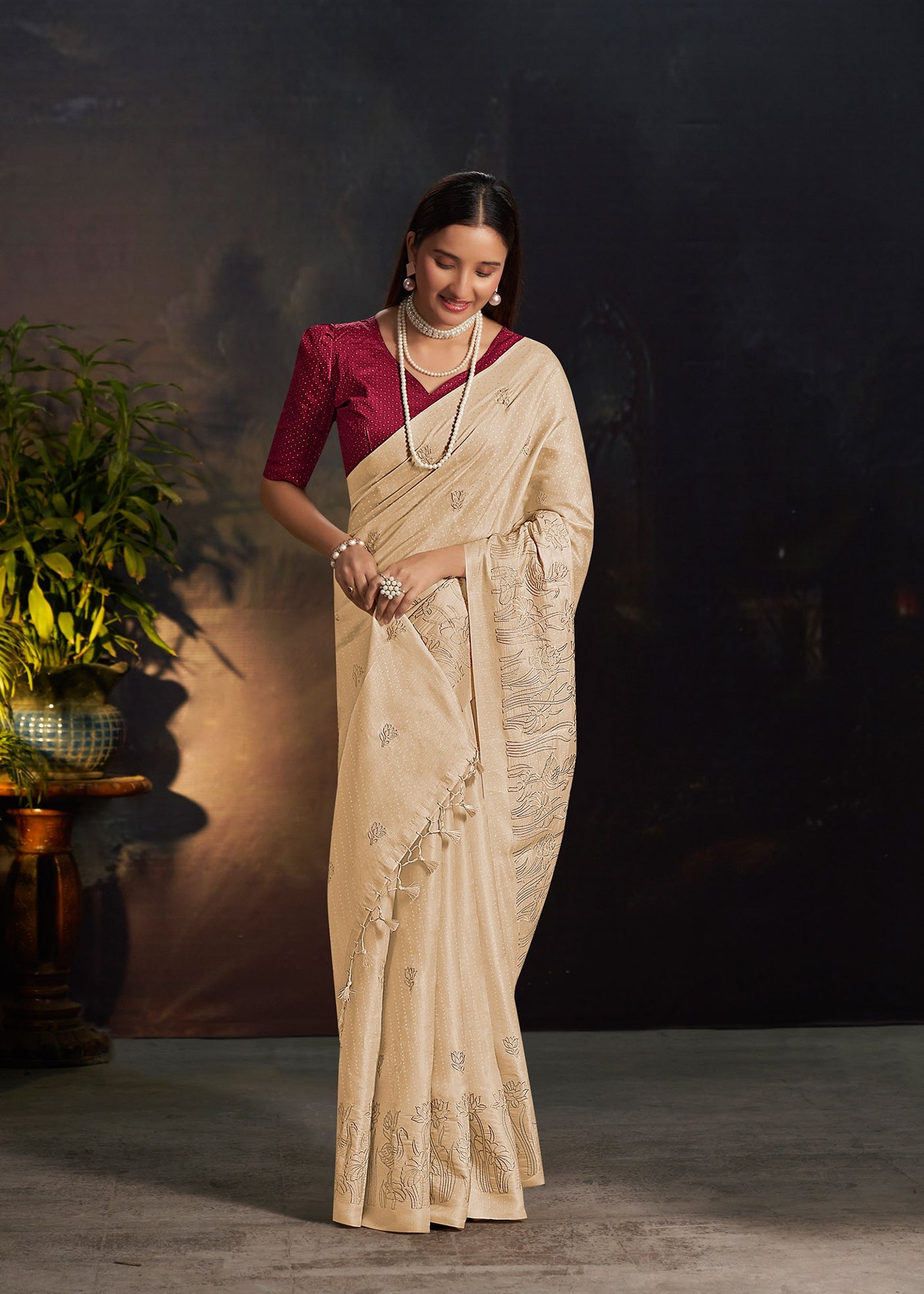 Beige silk saree with embroidered motifs along the border and pleated drape