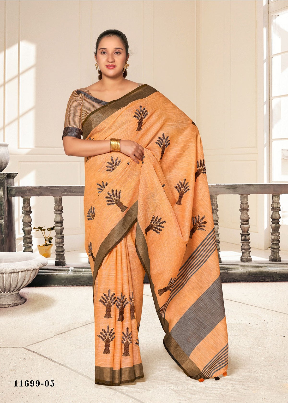 Cotton fancy saree in peach orange with black tree motifs and gray border.