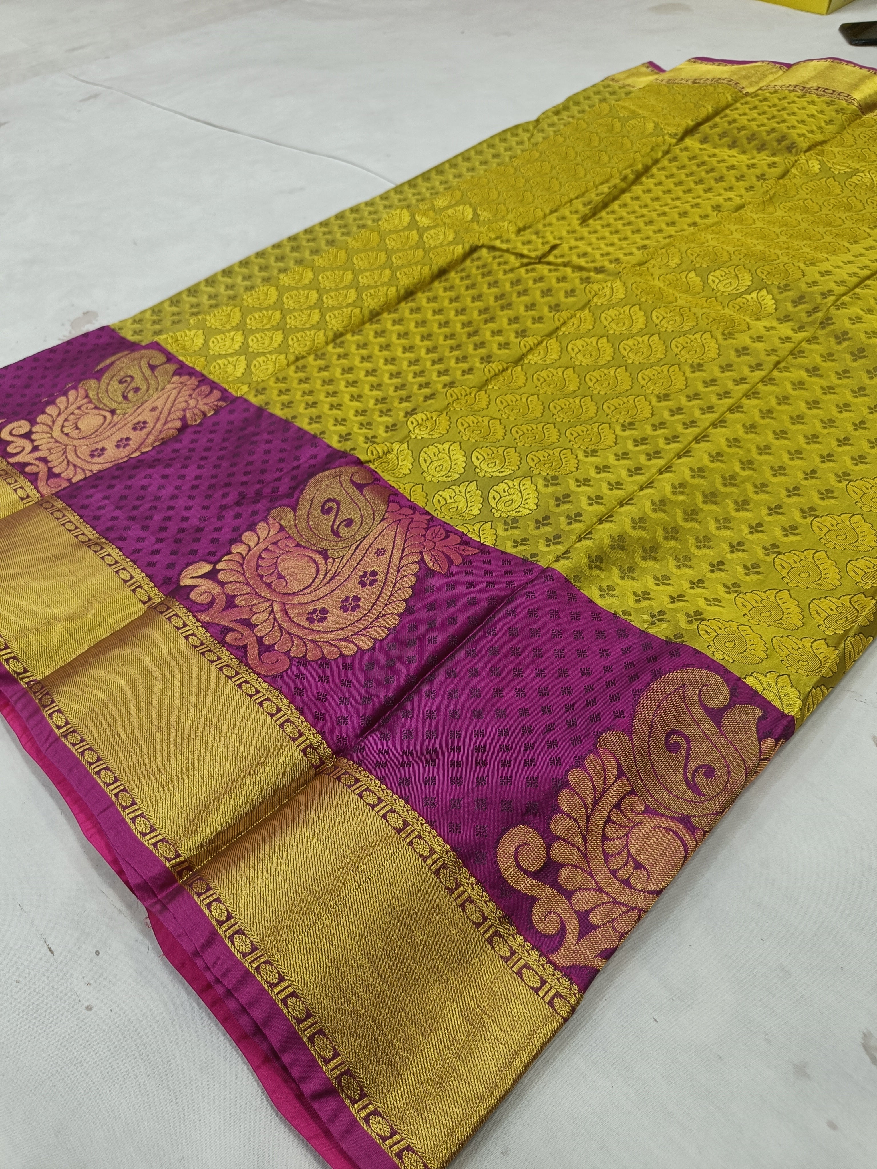 Olive-gold silk saree with purple border and paisley-style motifs, flat lay