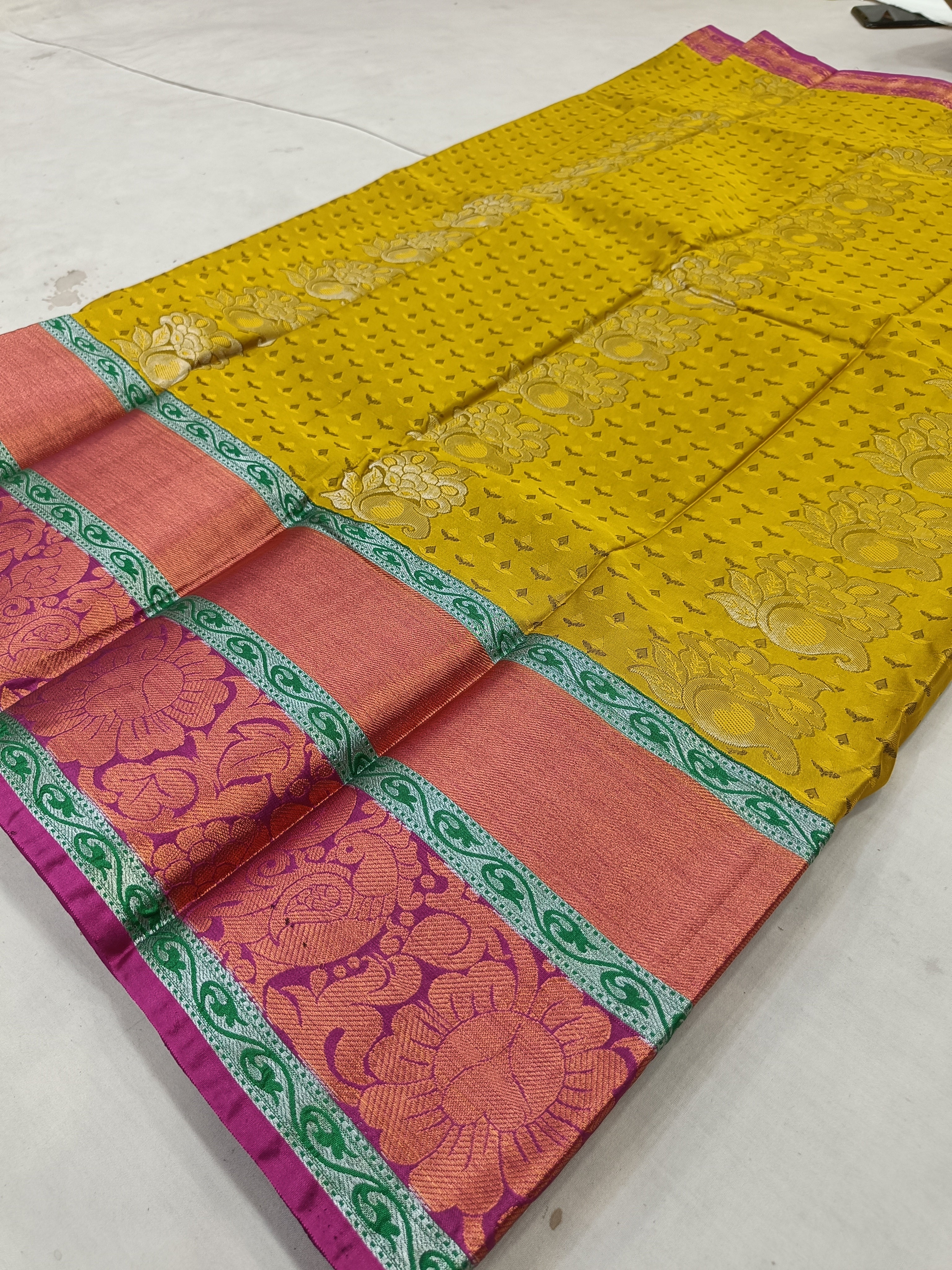 Yellow Kanchipuram silk saree with pink yoke, green border, patterned fabric