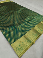 Dark green saree fabric with dotted geometric pattern and gold zari border, laid flat