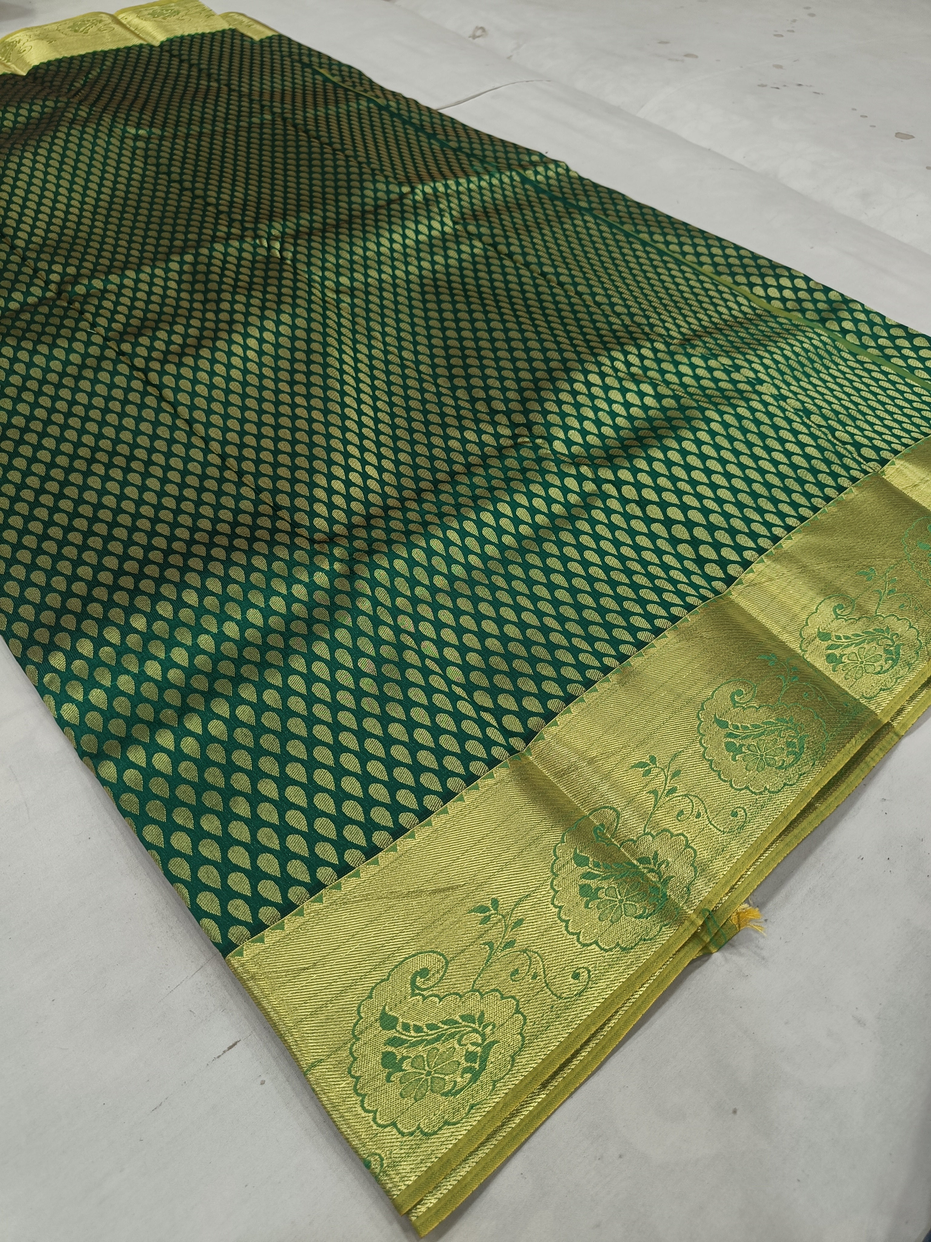 Dark green saree fabric with dotted geometric pattern and gold zari border, laid flat