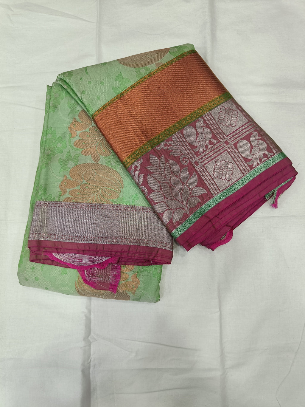 Folded mint green silk saree with maroon-gold border and patterned pallu
