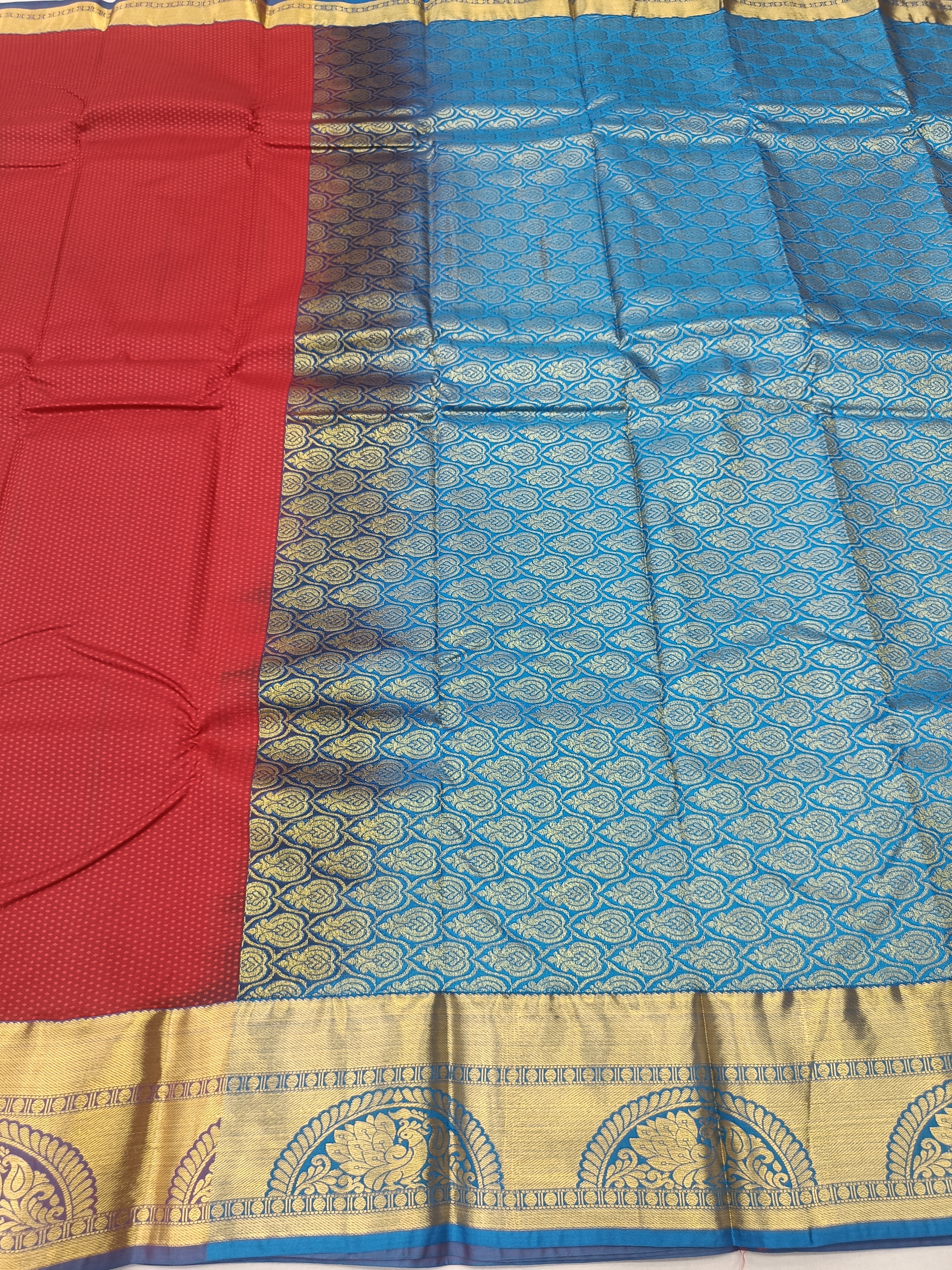 Red and blue silk saree fabric with intricate gold motifs and woven border