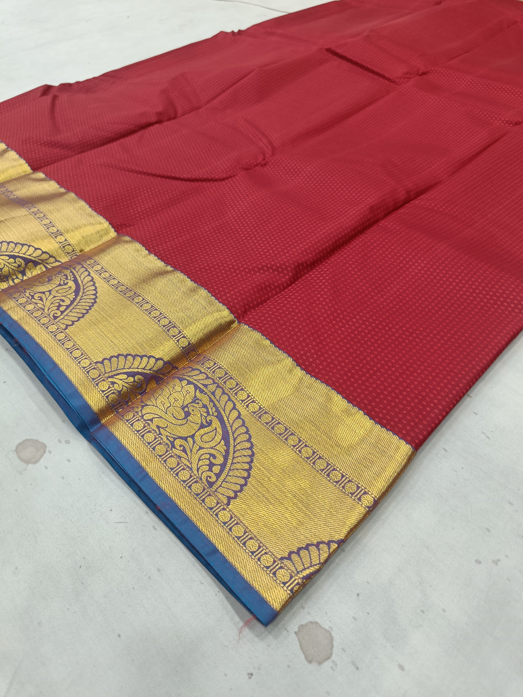 Red silk saree fabric with gold-and-blue border and ornate medallion band