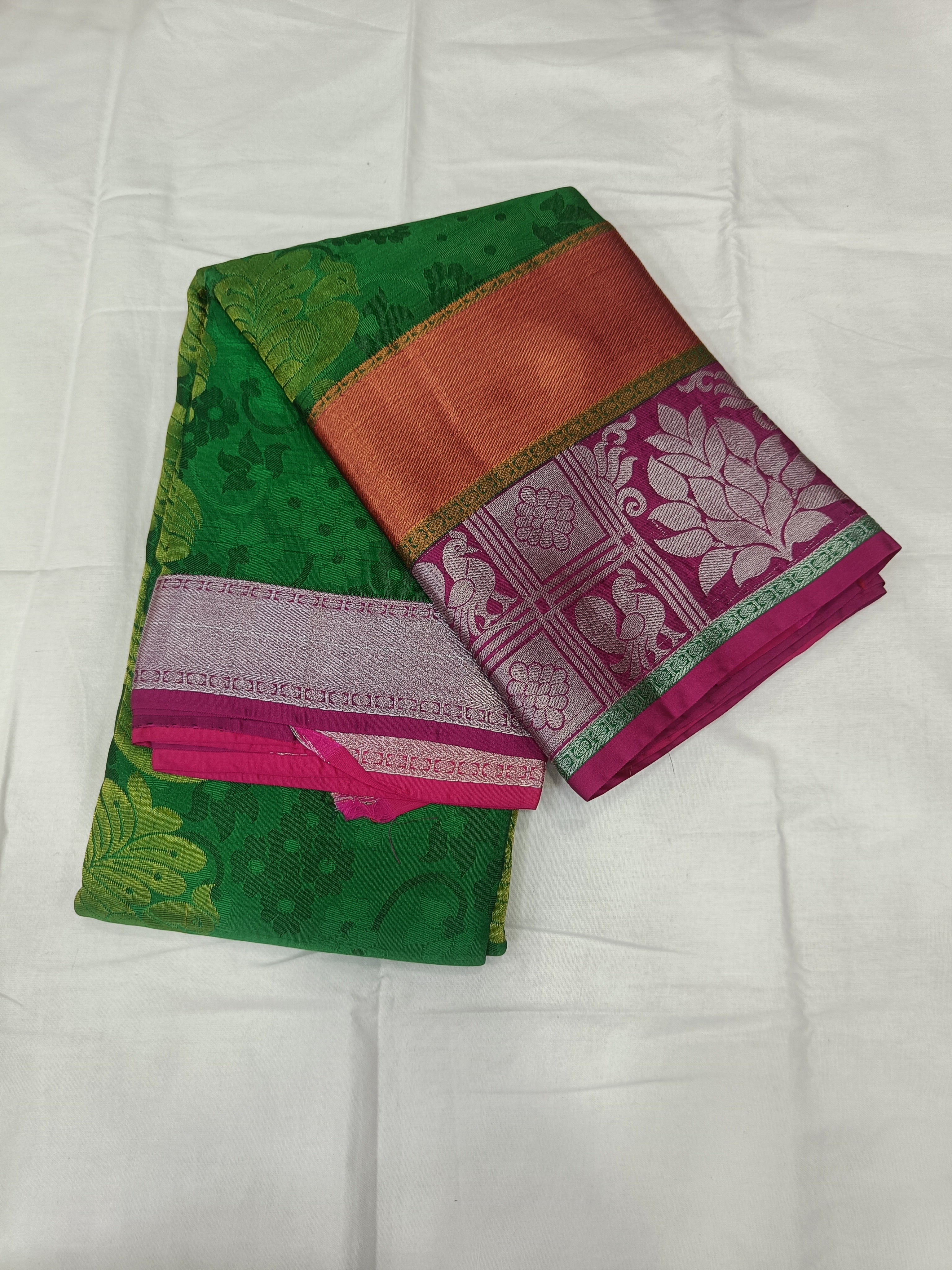 Folded green Kanchipuram silk saree with pink border and gold trim