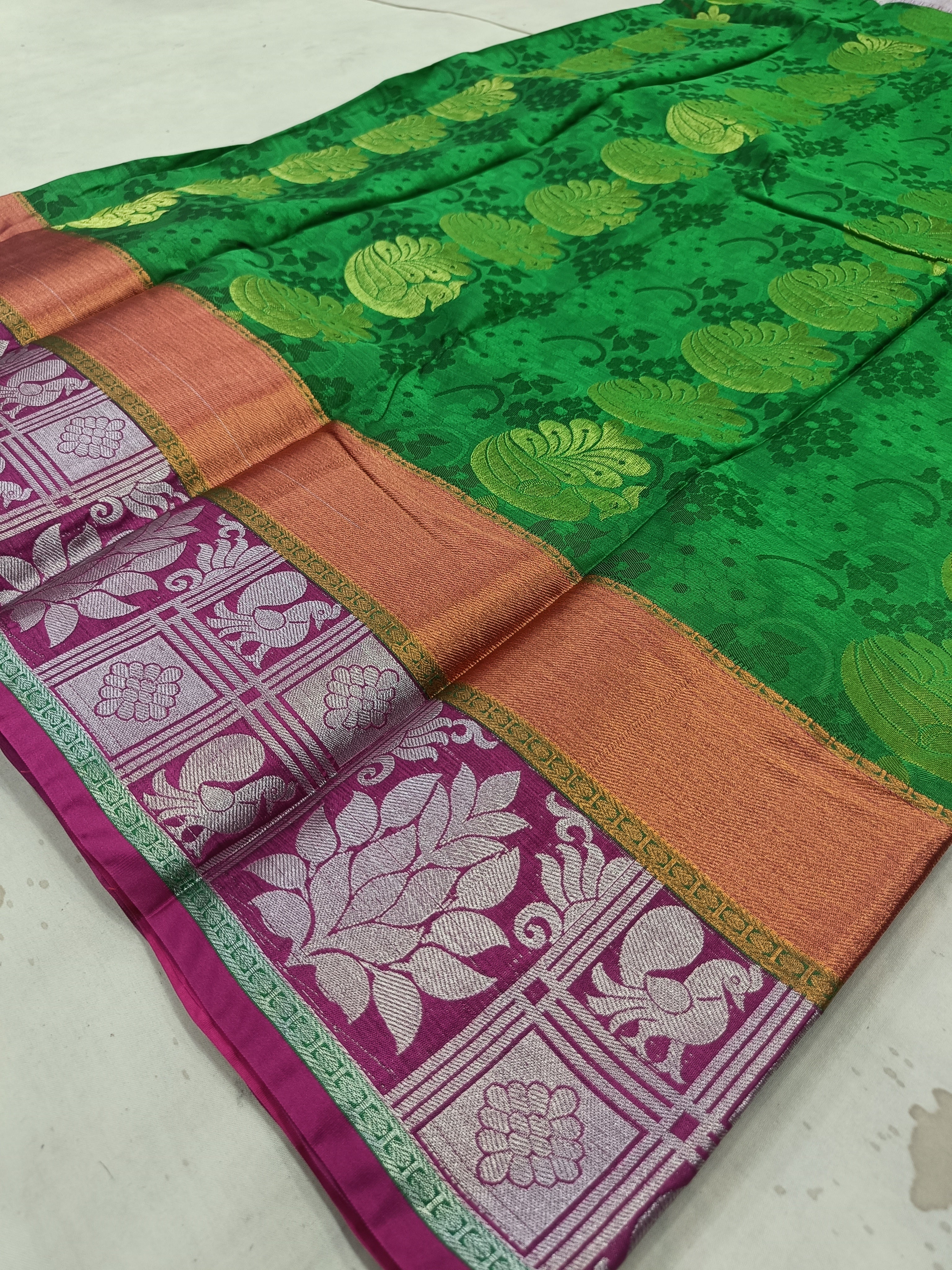 Saree border detail in green, pink, and gold with floral woven motifs