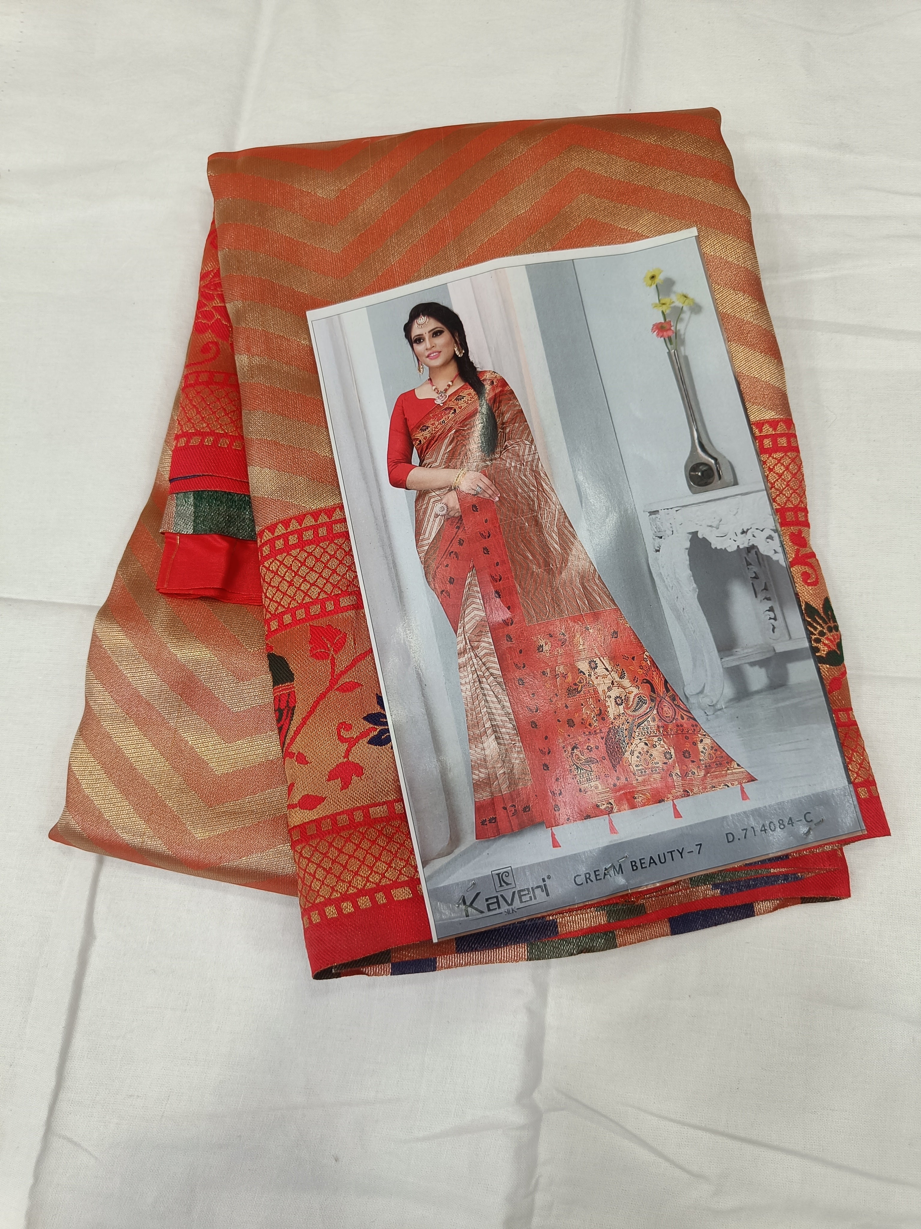 Folded Banarasi silk saree with red and brown zigzag print, shown with cover card