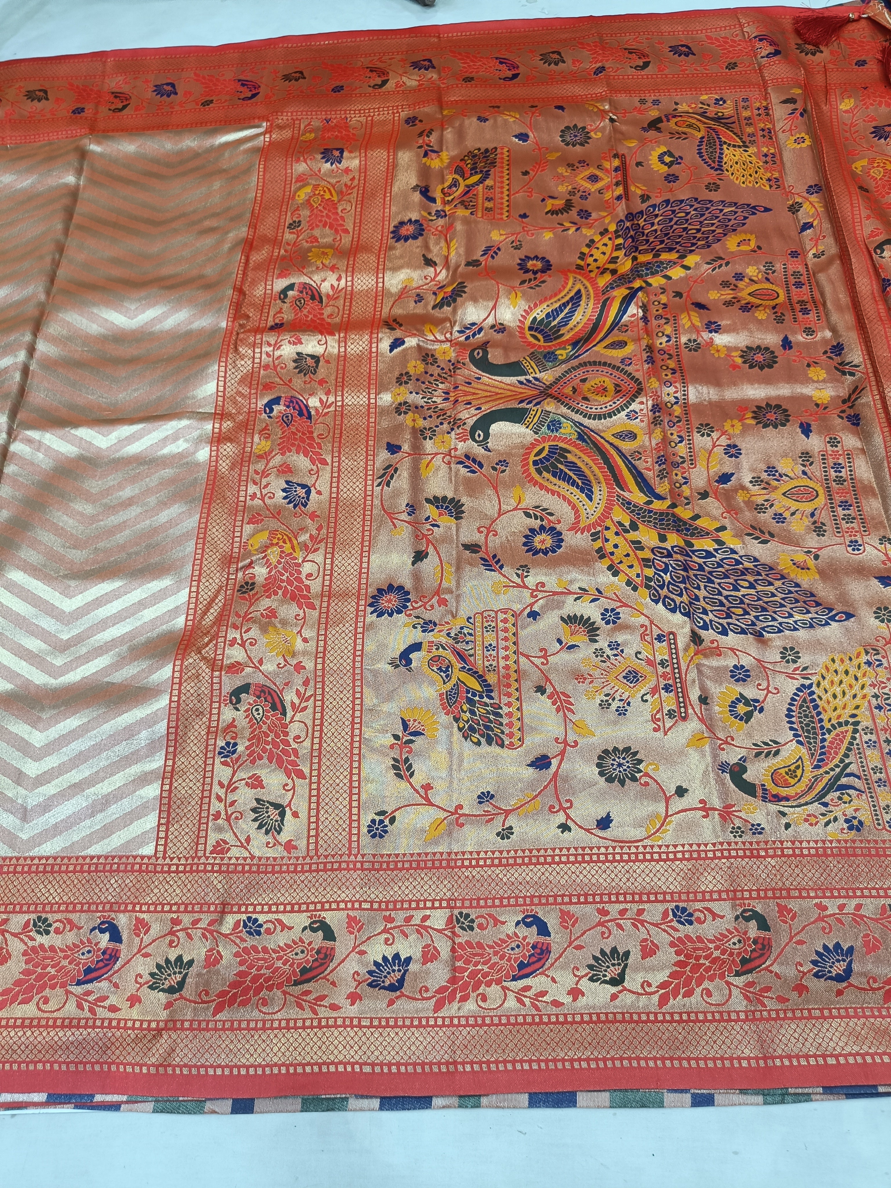 Banarasi silk saree fabric close-up with paisley and floral motifs, red border