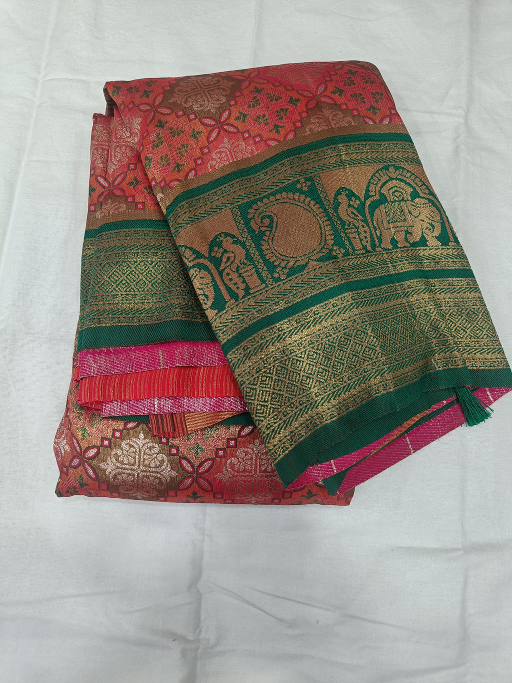 Draped pink saree with green-gold border, ornate motifs, and contrasting blouse panel