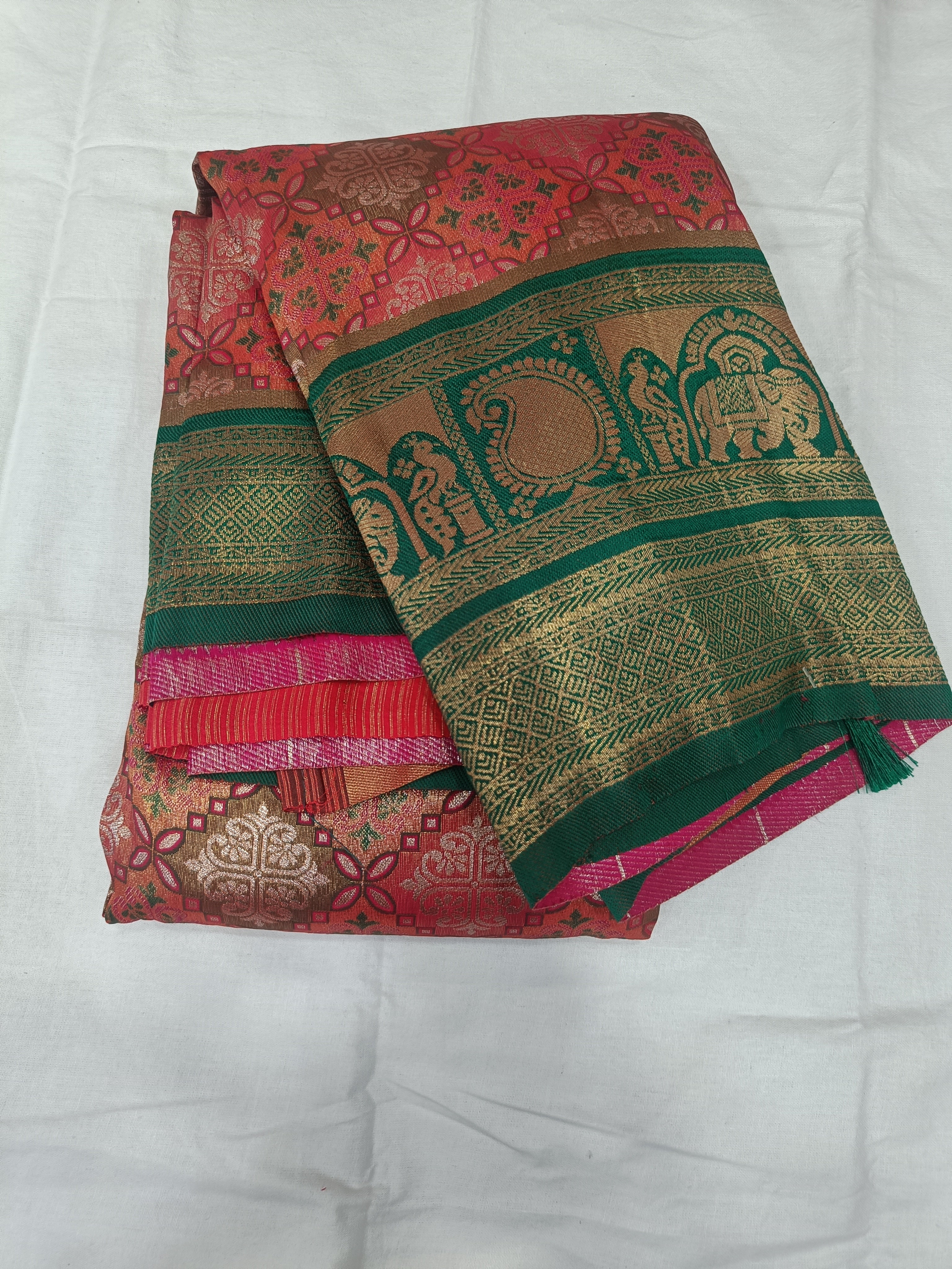 Draped pink saree with green-gold border, ornate motifs, and contrasting blouse panel