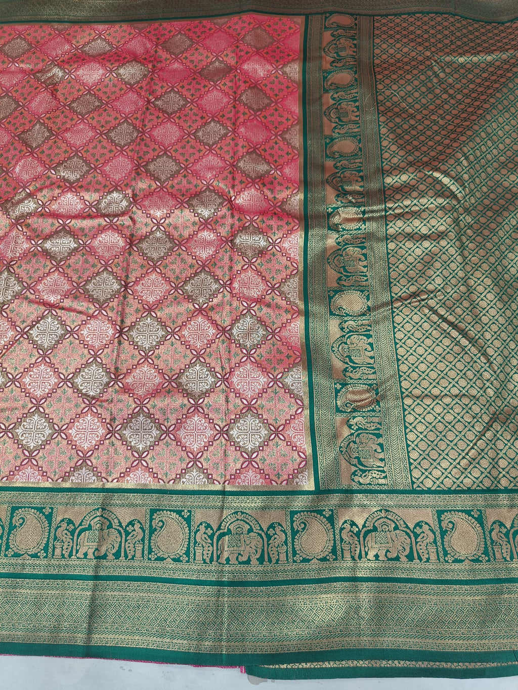 Close-up of pink and green saree border with woven motifs and diamond pattern field
