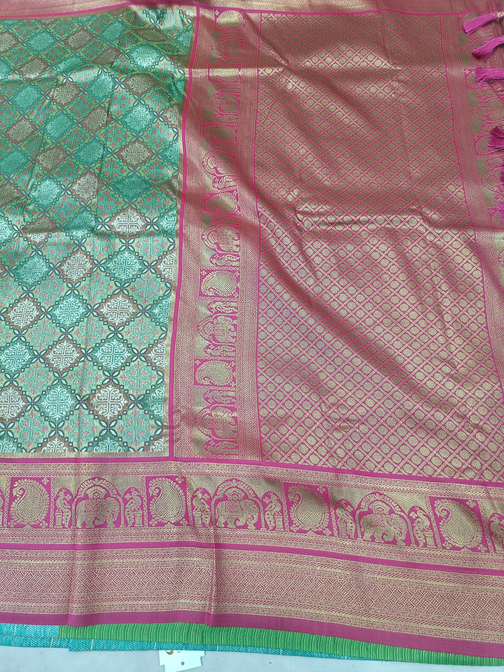 Banarasi silk saree close-up: teal pattern, pink panel, magenta border, gold motifs