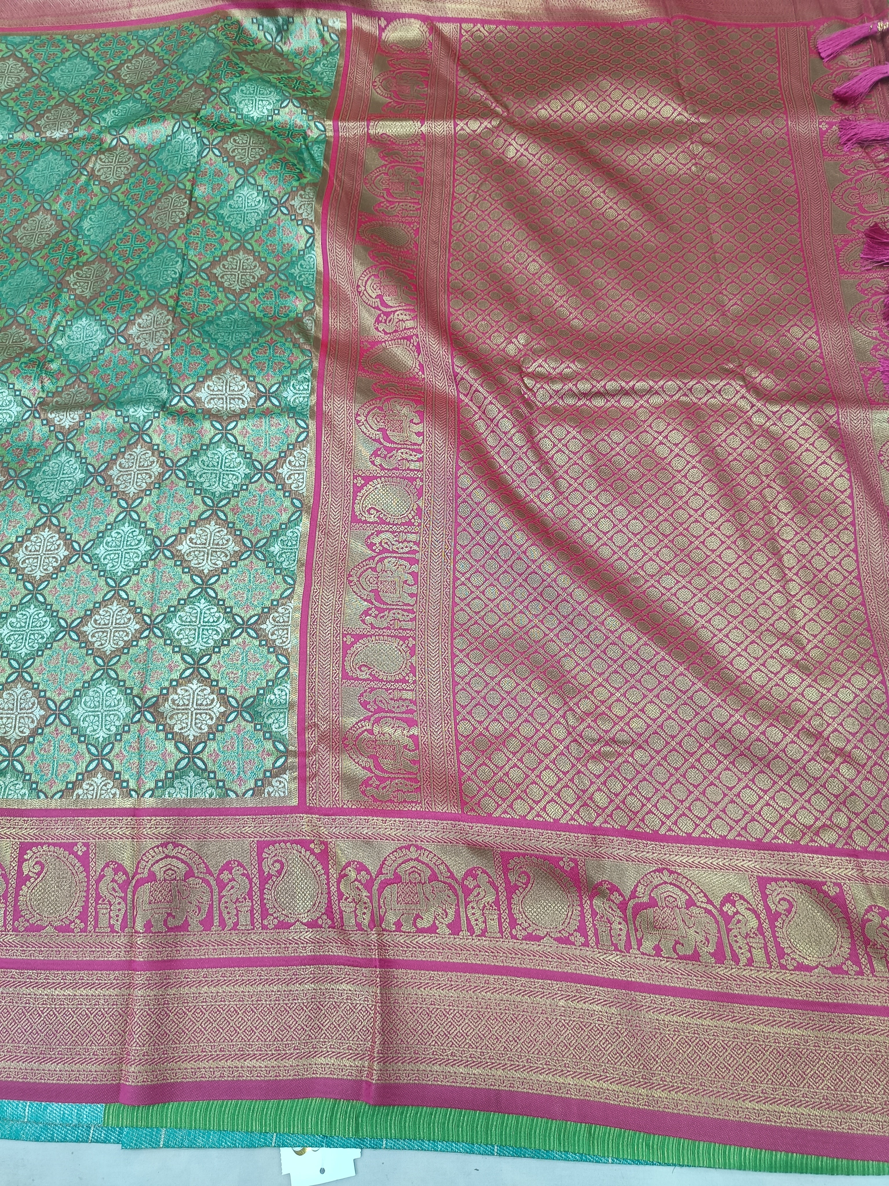 Banarasi silk saree close-up: teal pattern, pink panel, magenta border, gold motifs