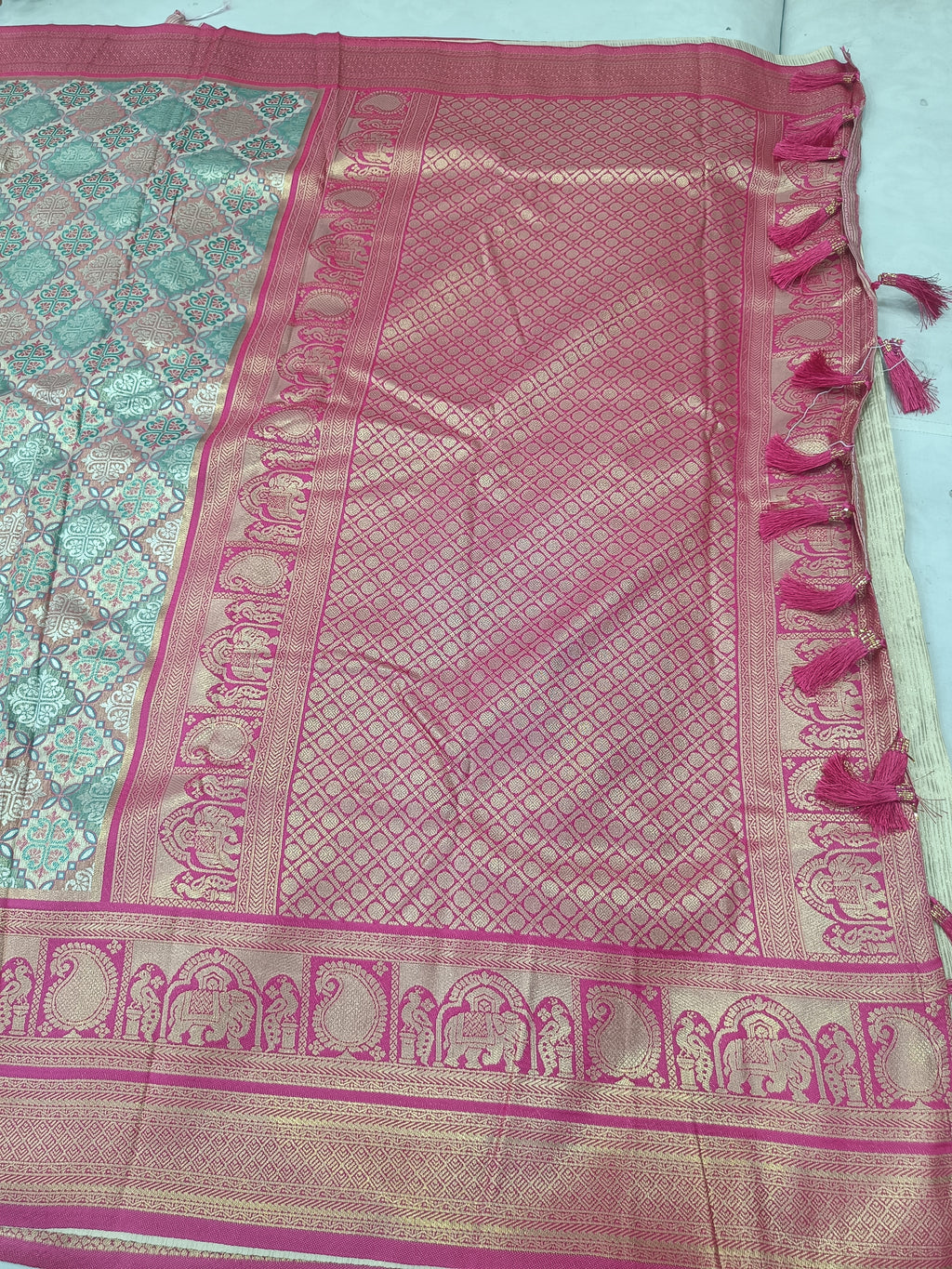 Silk saree pallu with pink lattice pattern border, ornate medallion details, fringed edges