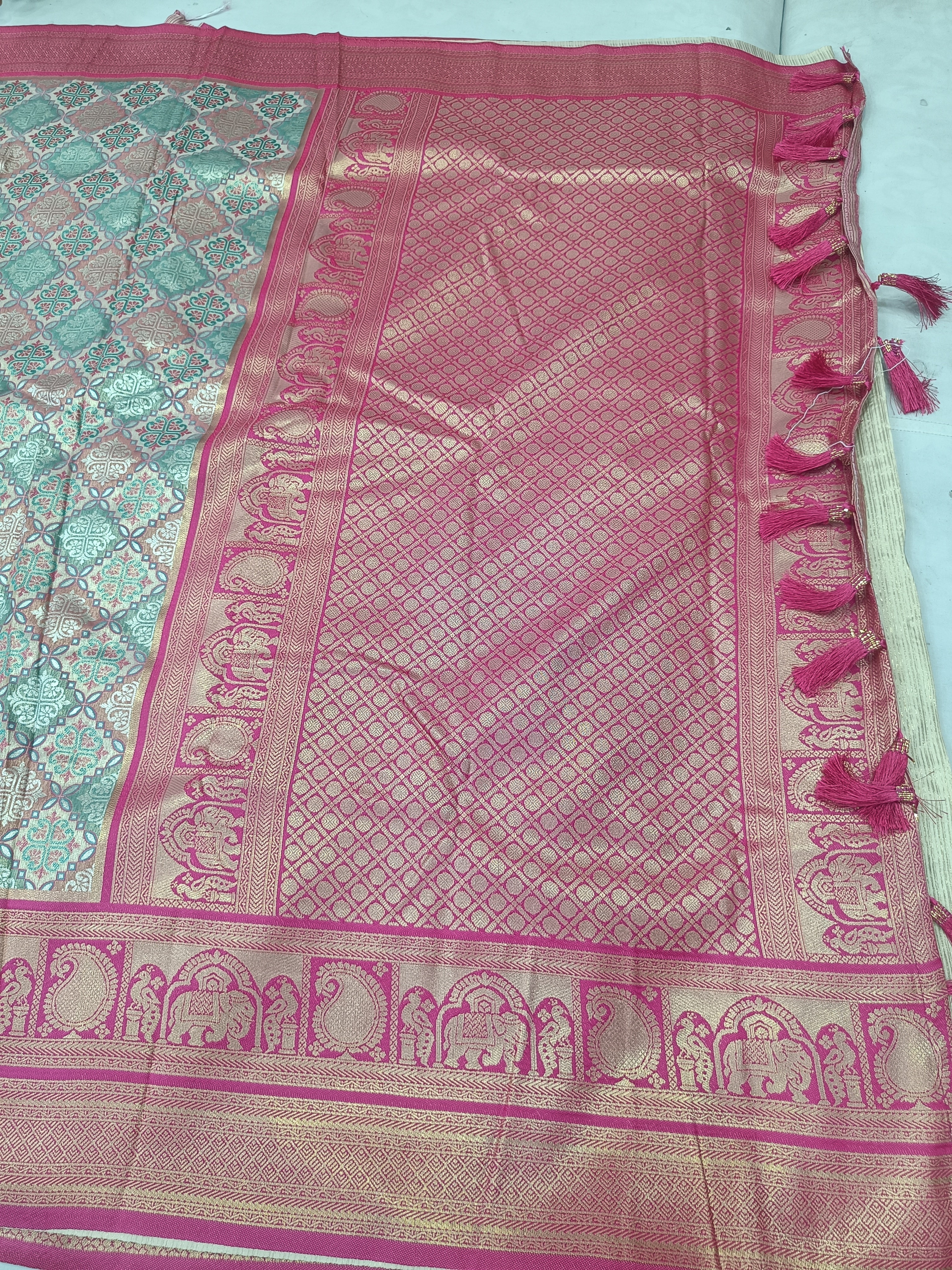 Silk saree pallu with pink lattice pattern border, ornate medallion details, fringed edges
