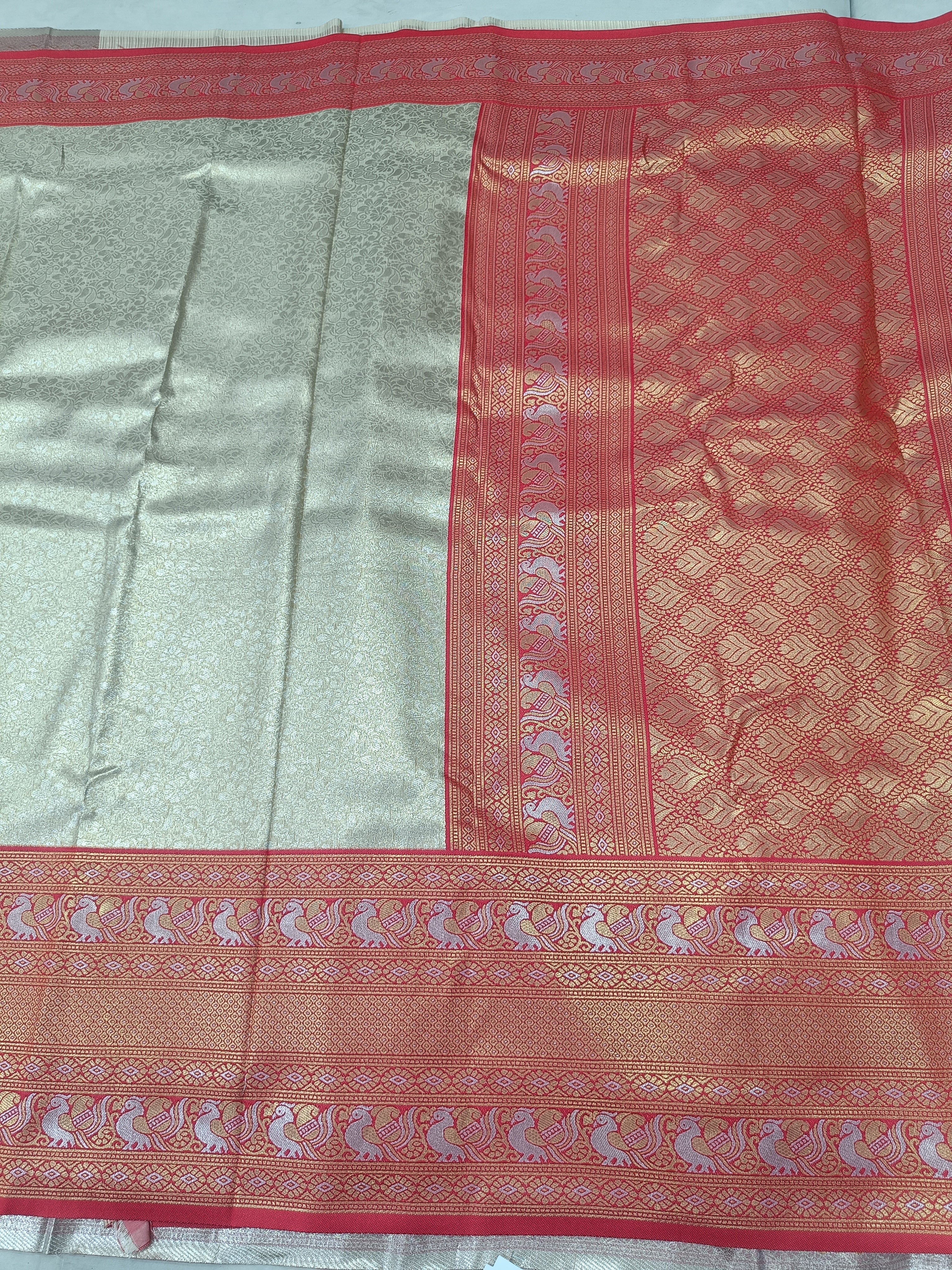 Silver silk saree with red woven border and geometric motifs, flat lay