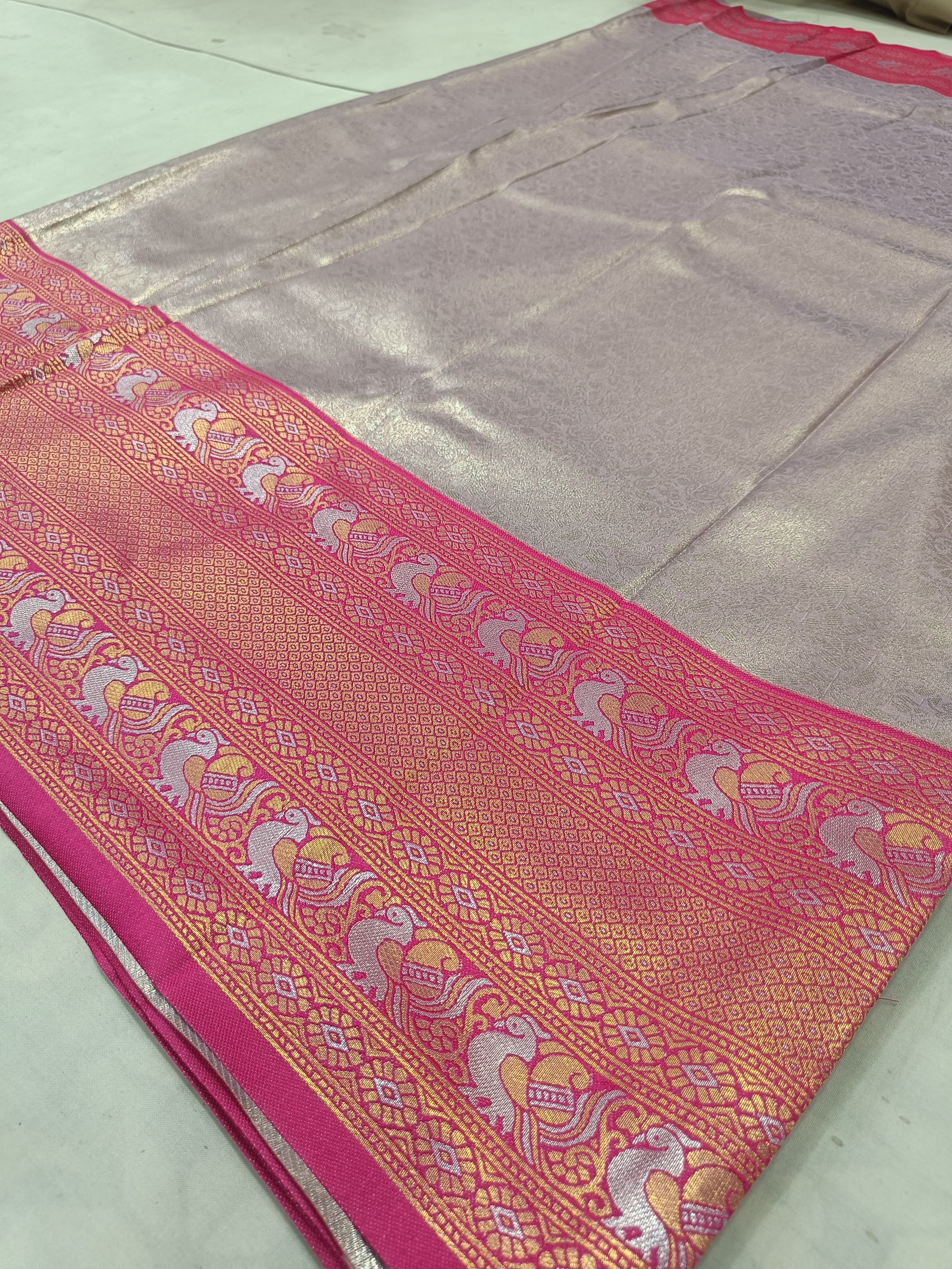 Pink Banarasi silk border with gold-toned temple motifs on light grey pallu