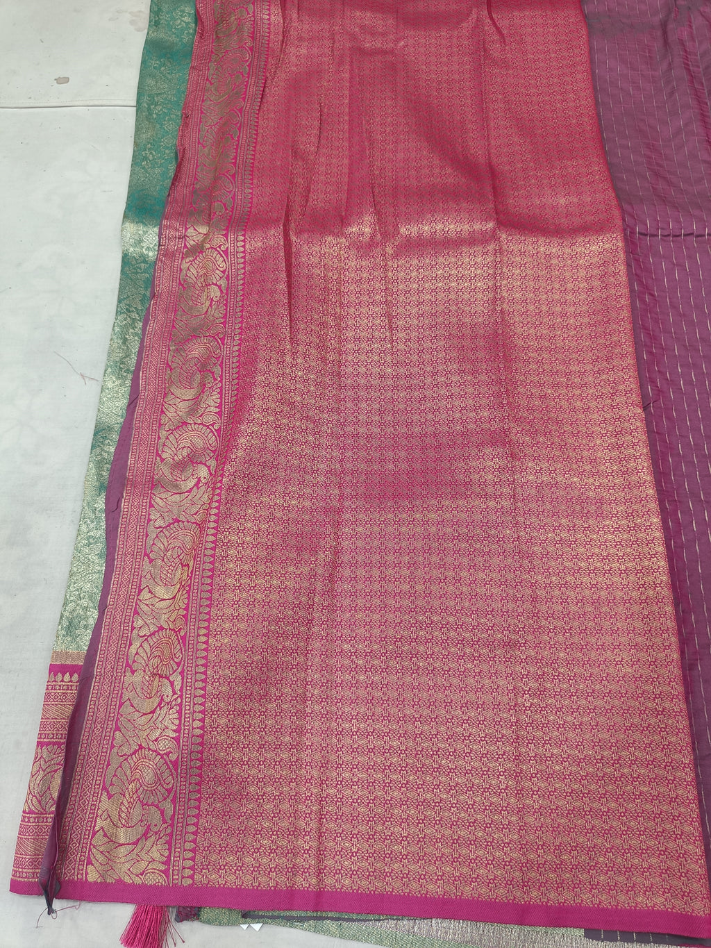 Teal green and magenta pink Banarasi silk saree with wide border and textured pattern