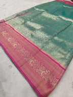Teal green Banarasi silk saree with pink ornate border and gold-style woven design