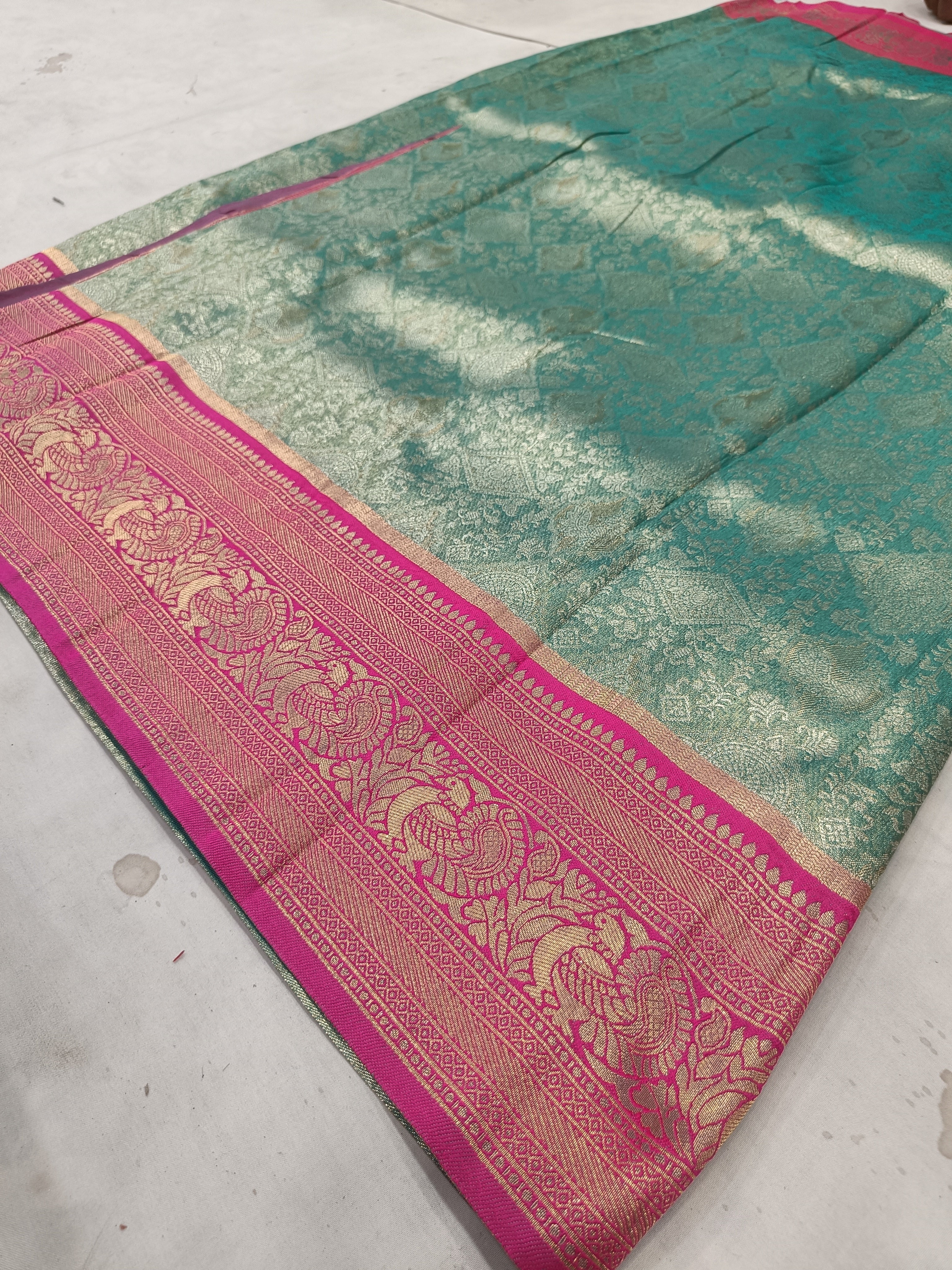 Teal green Banarasi silk saree with pink ornate border and gold-style woven design