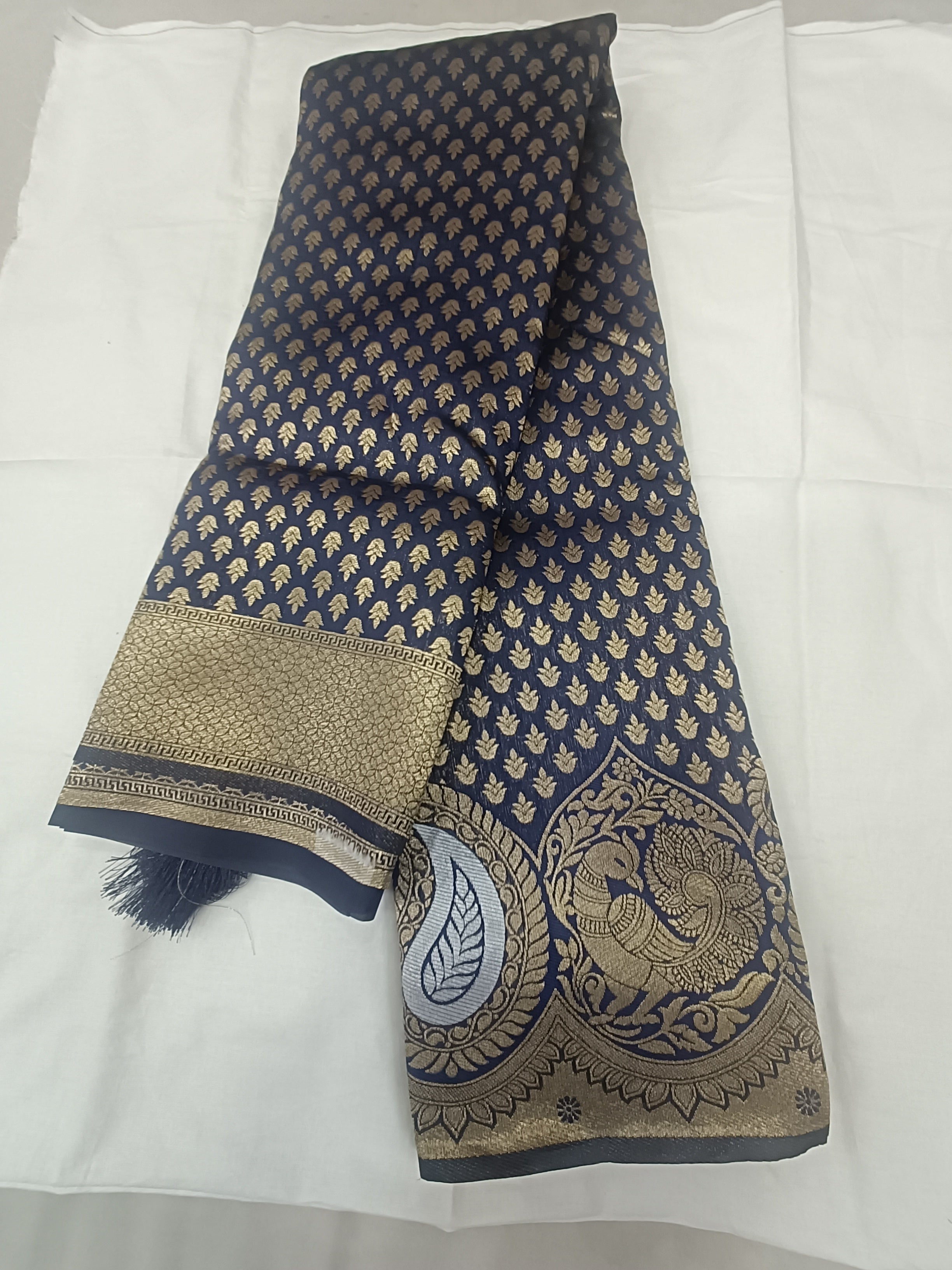 Folded navy blue Banarasi silk saree with gold motif body and ornate border hem