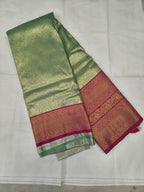 Folded mint green silk saree with pink zari border and textured woven fabric
