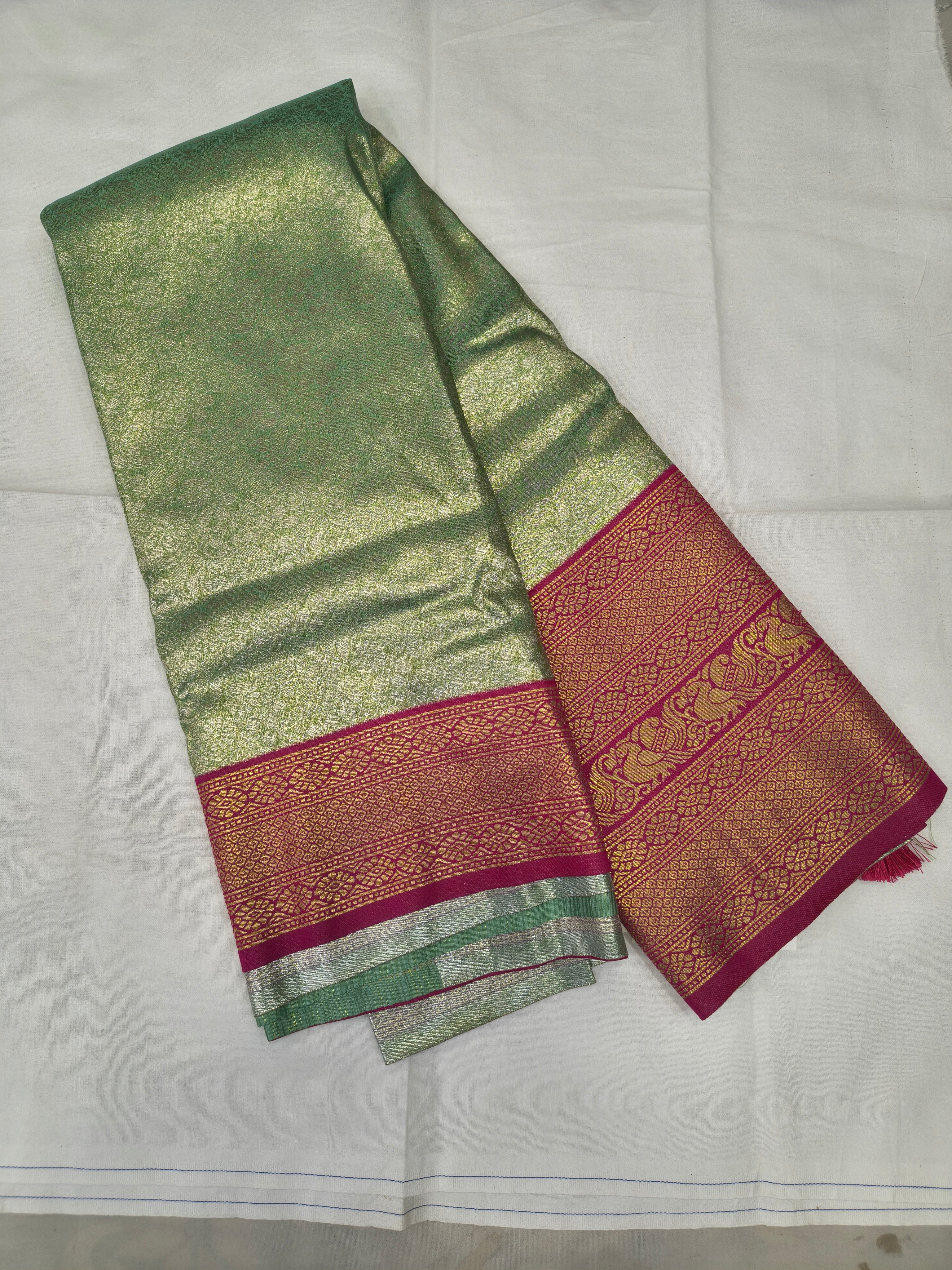 Folded mint green silk saree with pink zari border and textured woven fabric