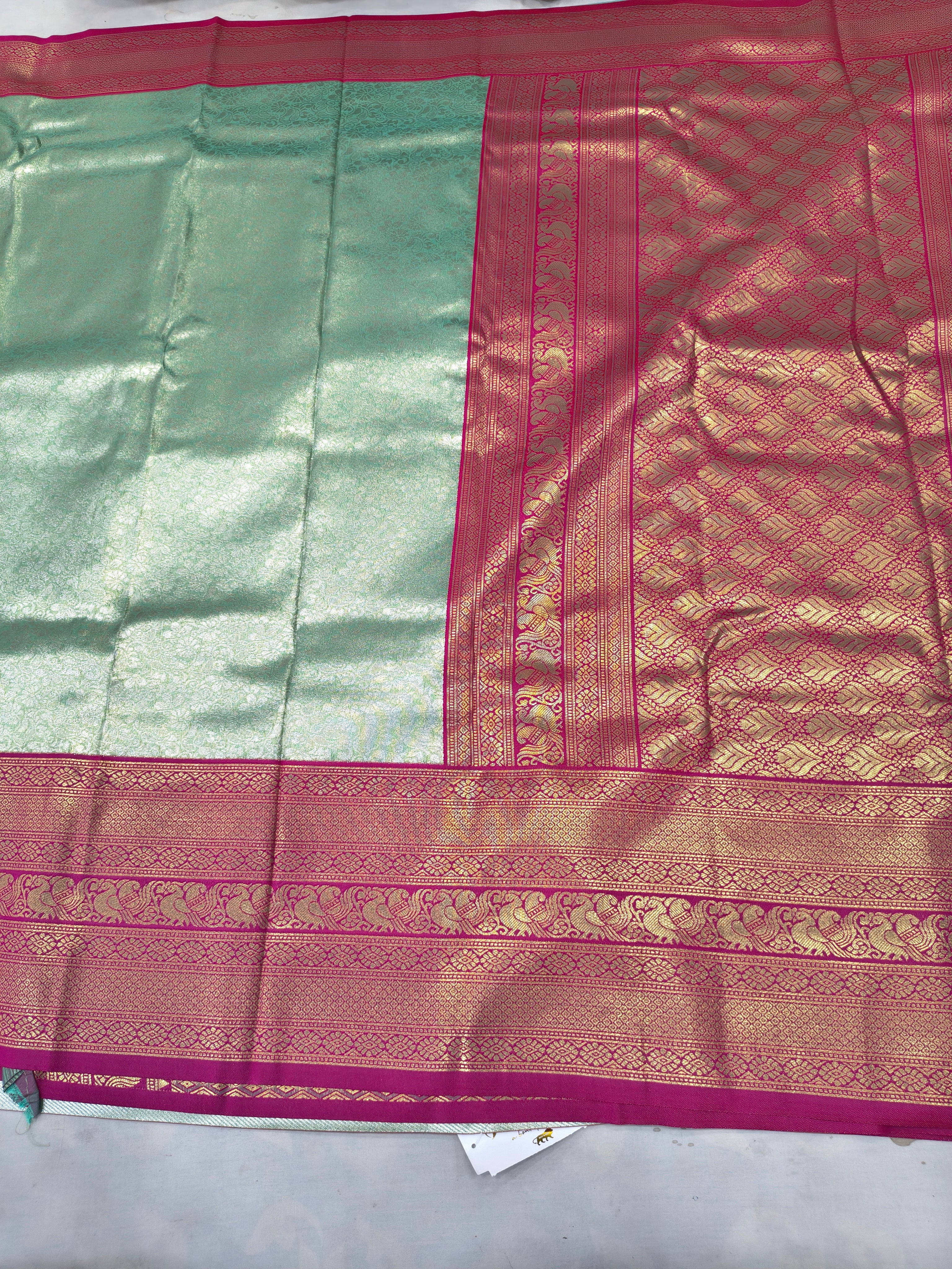 Close-up of mint green and pink Banarasi-style silk saree border with woven designs