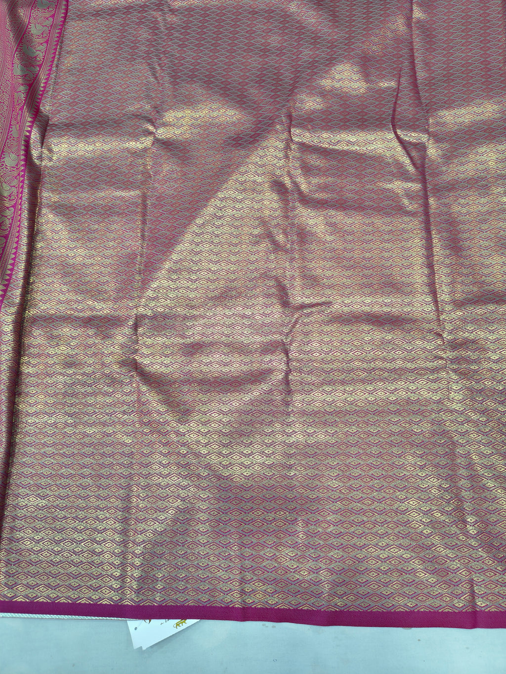 Close-up of pink patterned silk saree with textured weave and thin border lines