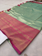 Mint green silk saree laid flat with pink pallu border and ornate woven motifs