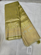 Olive green saree with cream-gold zari border folded, with fabric tag visible