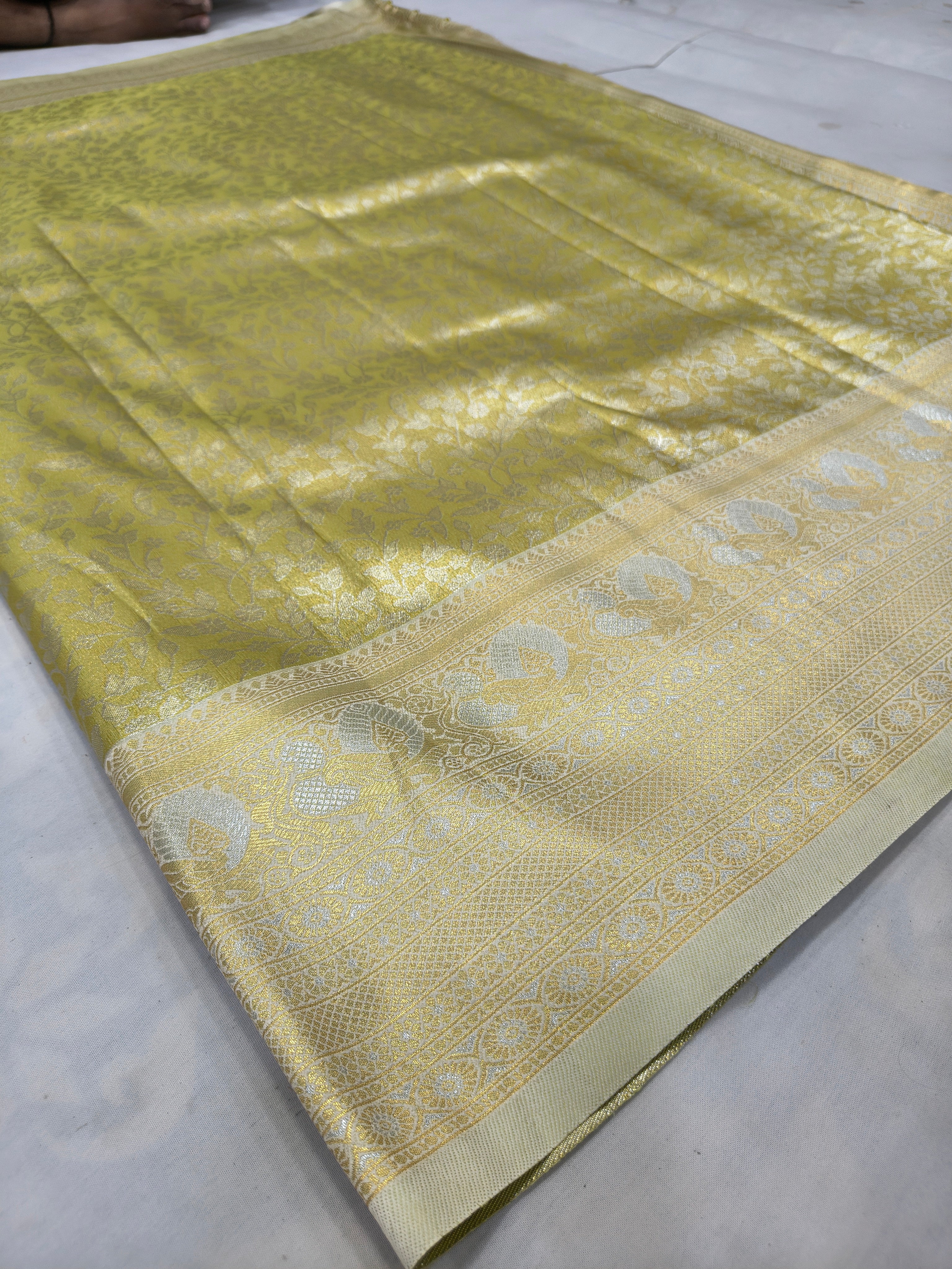 Olive green silk saree with gold-toned motifs and zari border laid flat