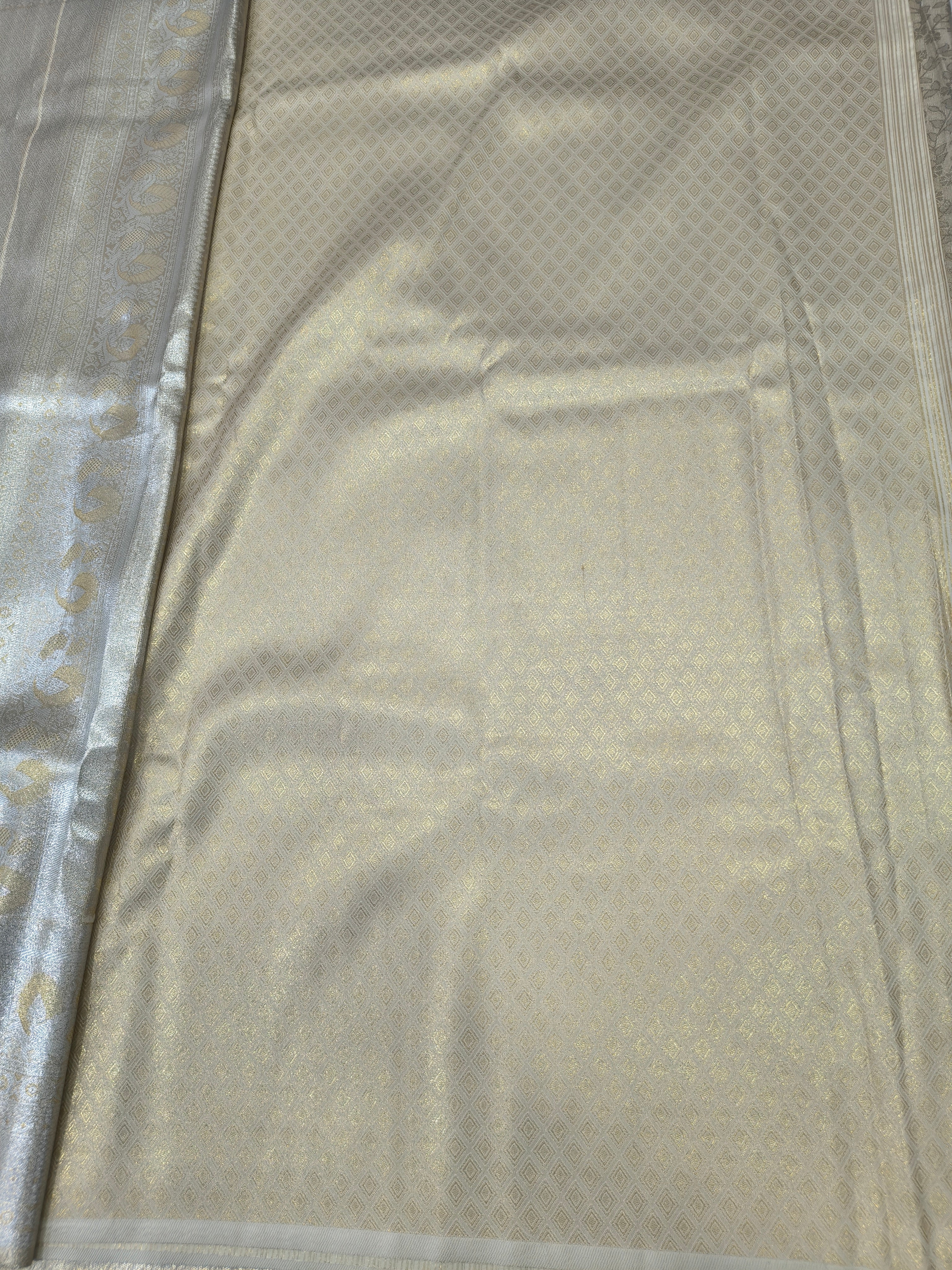 Cream Banarasi silk saree fabric with subtle gold motifs and zari border detail