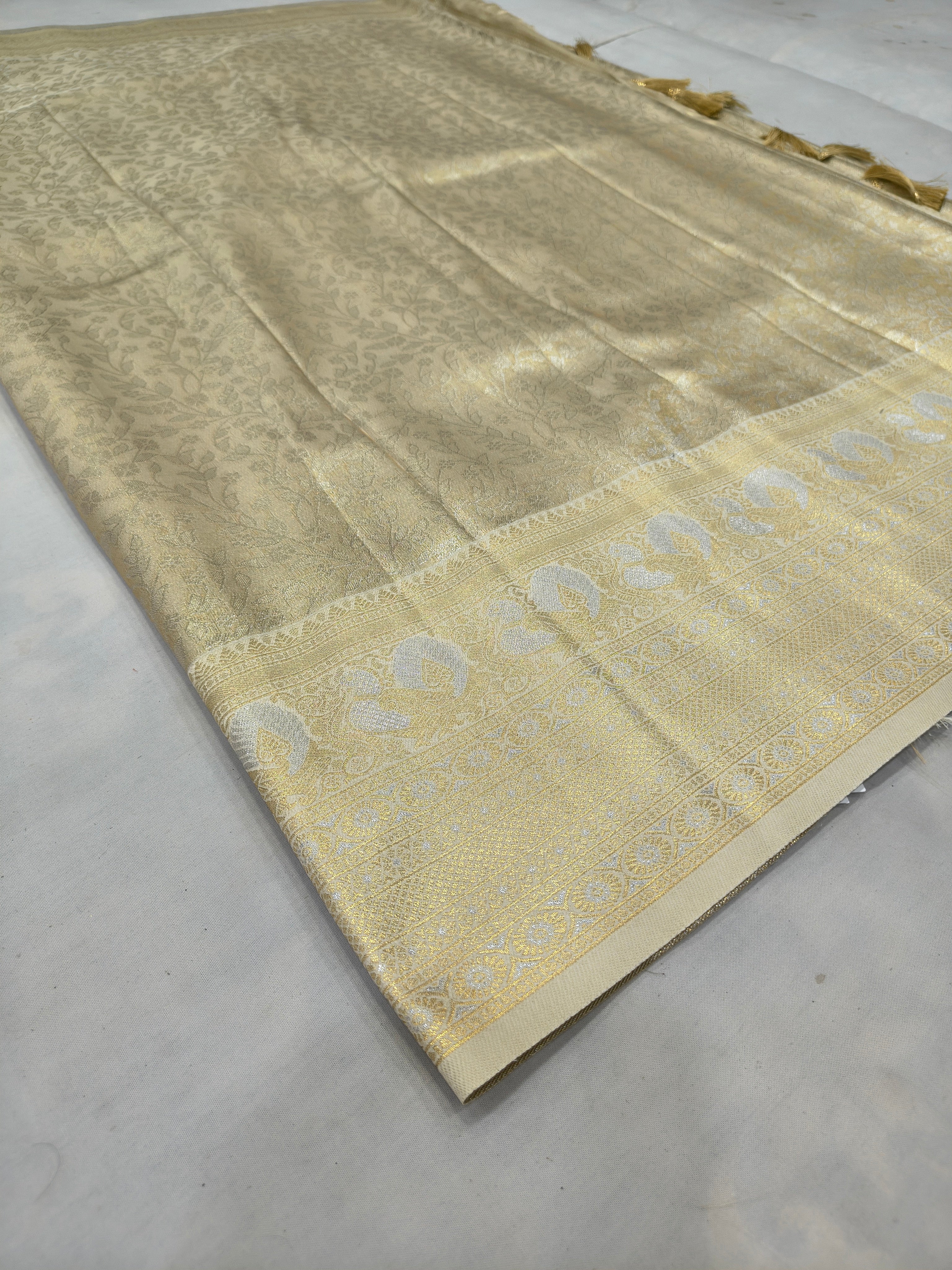 Cream and gold Banarasi silk saree fold with ornate zari border on one edge
