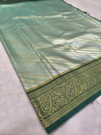 Teal and olive green Banarasi silk saree folded with zari stripes and gold border