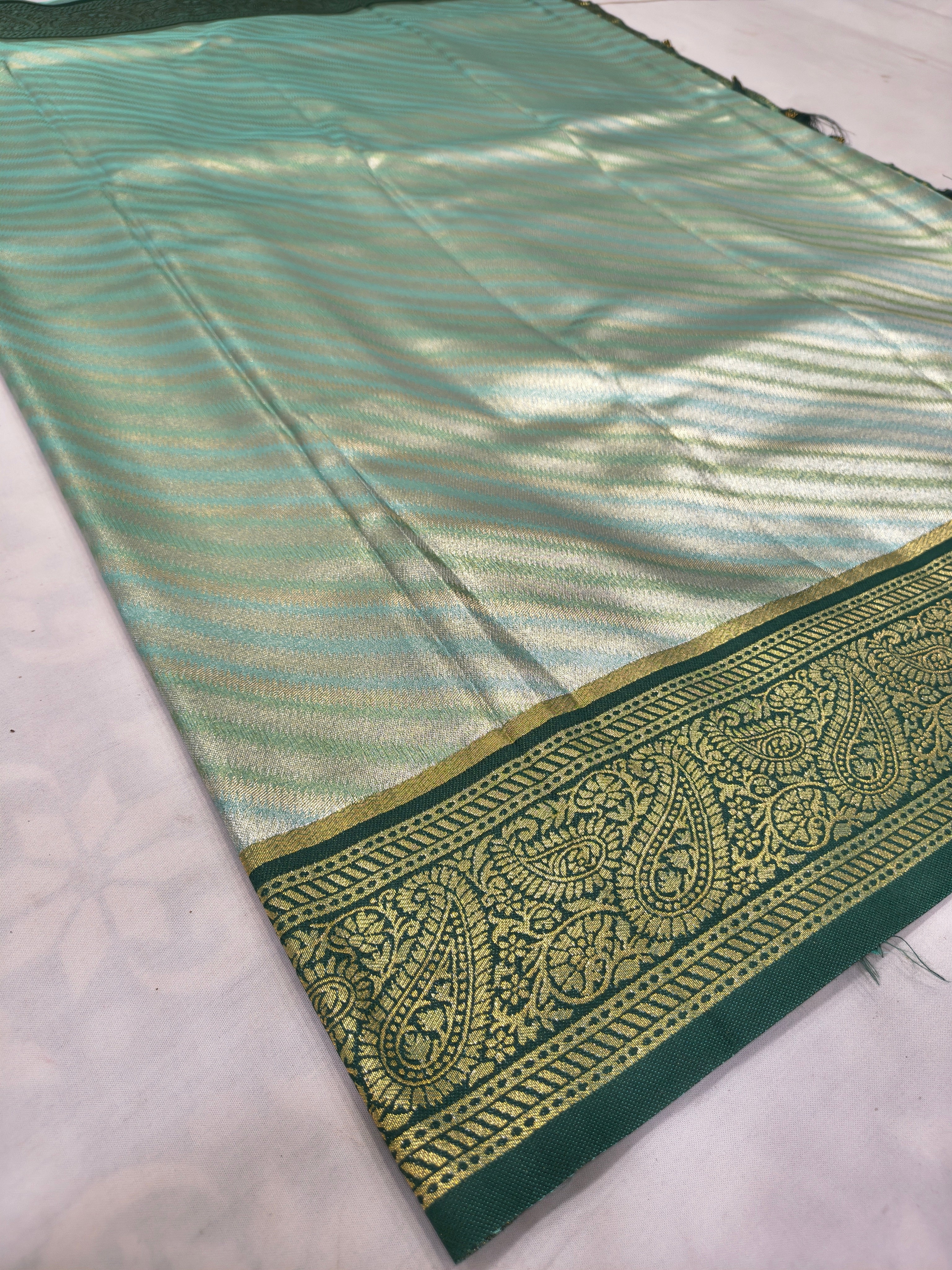 Teal and olive green Banarasi silk saree folded with zari stripes and gold border