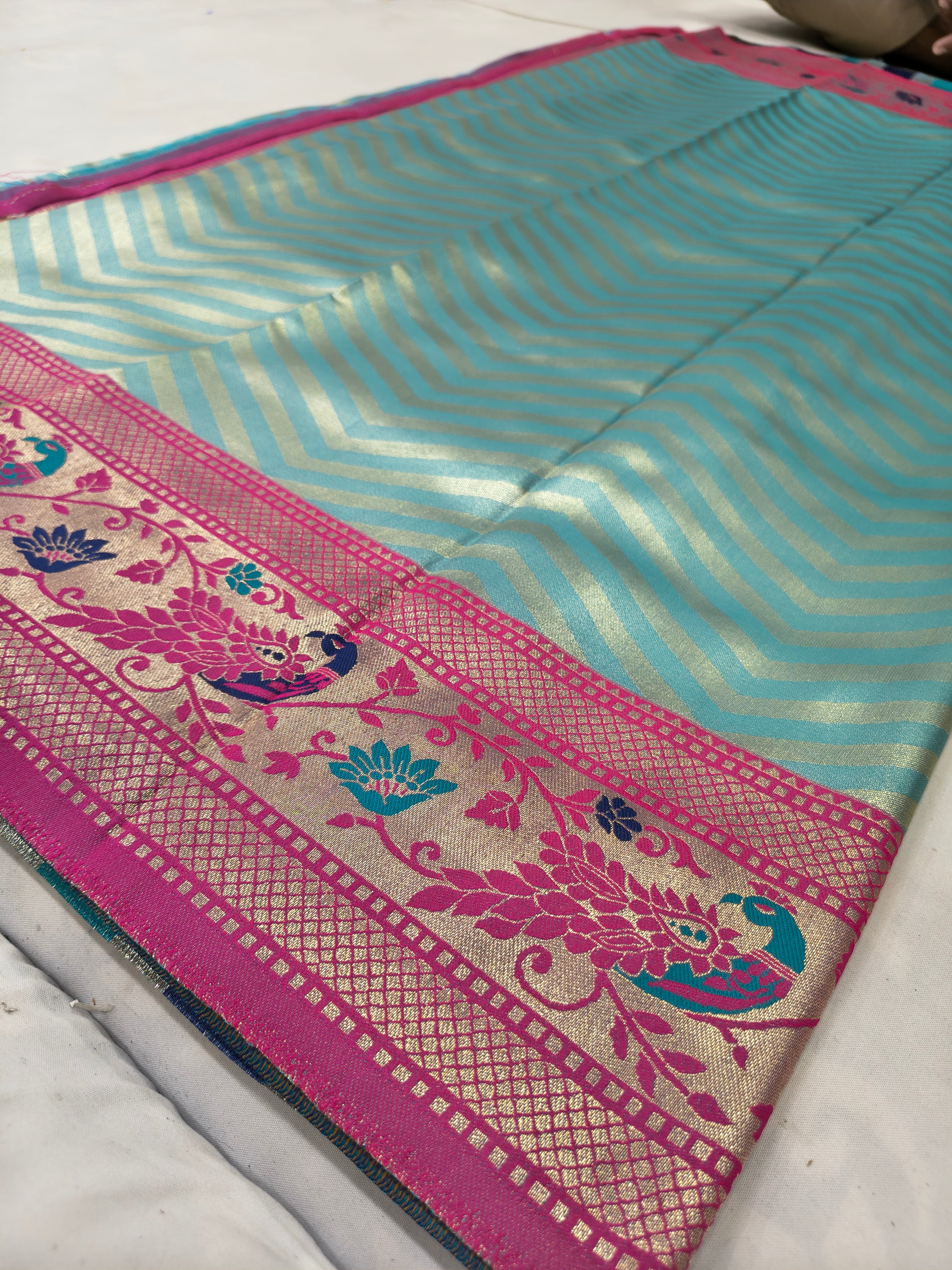 Teal and blue zigzag Banarasi silk saree with magenta floral border and woven trim