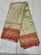 Cream Banarasi silk saree with red-gold woven border, folded with visible pallu edge