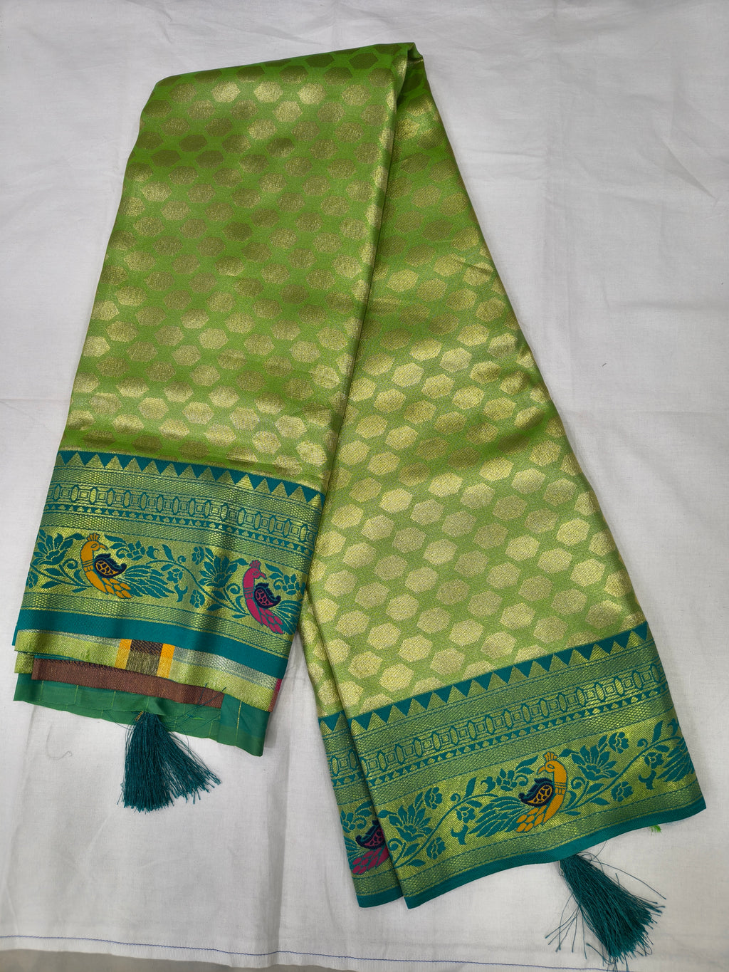 Folded green Banaras silk saree with blue border and tassels