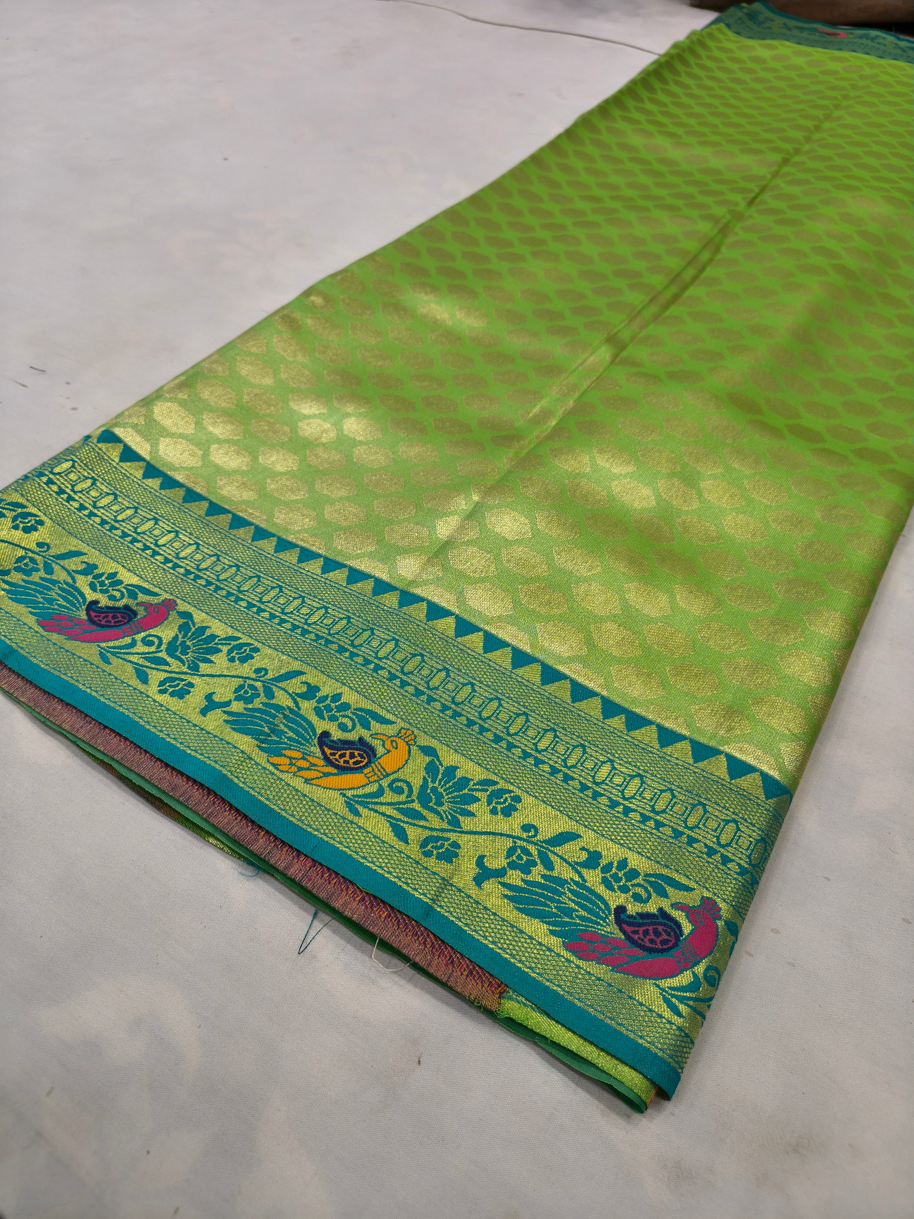 Laid flat green silk saree with blue border and ornate zari-style trim