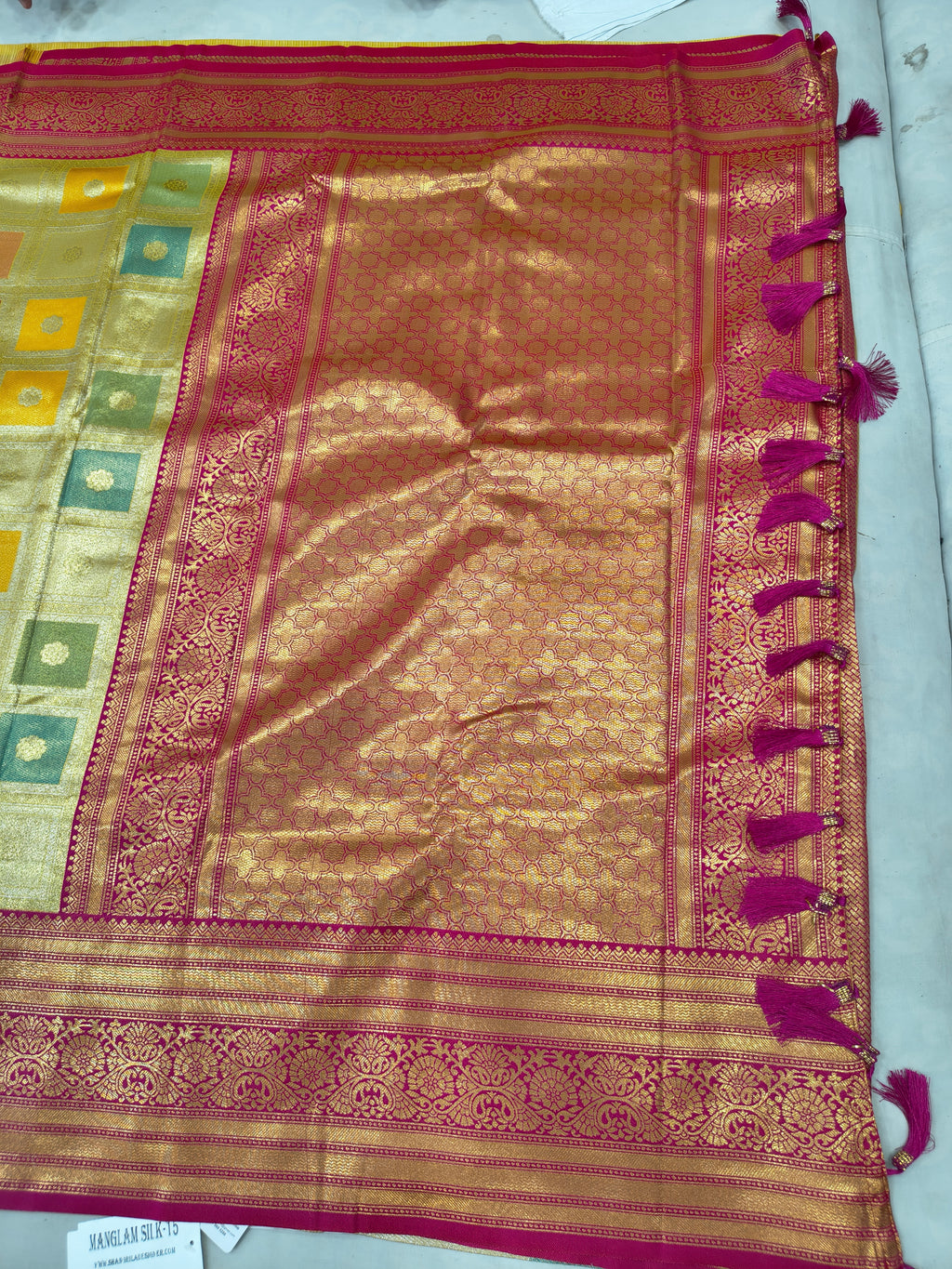 Banarasi silk saree close-up with gold sheen, pink border, and square woven motifs