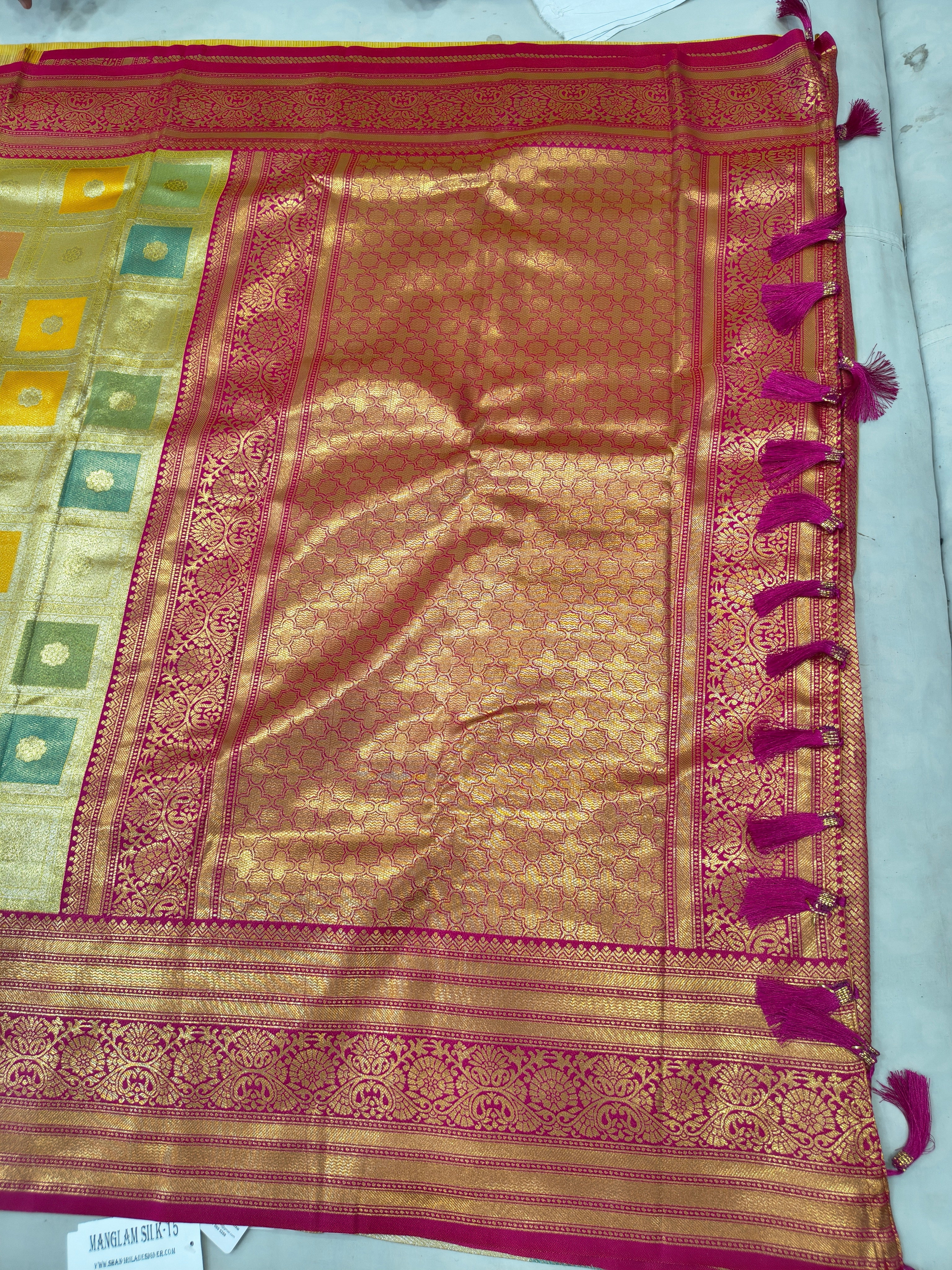 Banarasi silk saree close-up with gold sheen, pink border, and square woven motifs