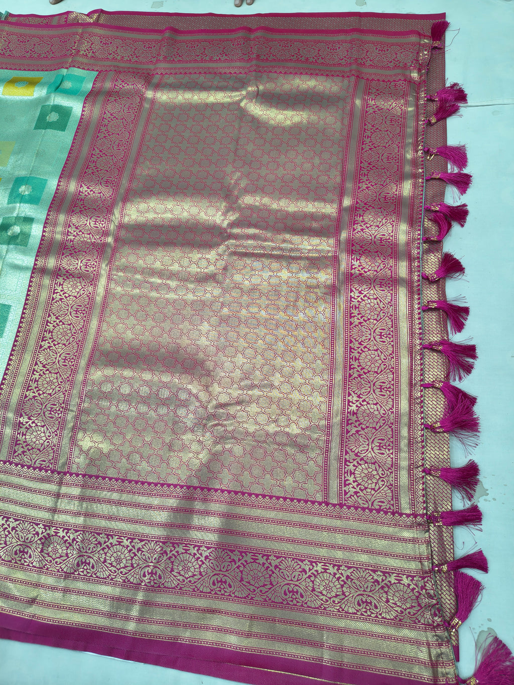 Pastel silk saree border detail with magenta trim and tassels, woven motifs