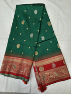 Teal green silk saree folded flat with small gold motifs and red patterned border