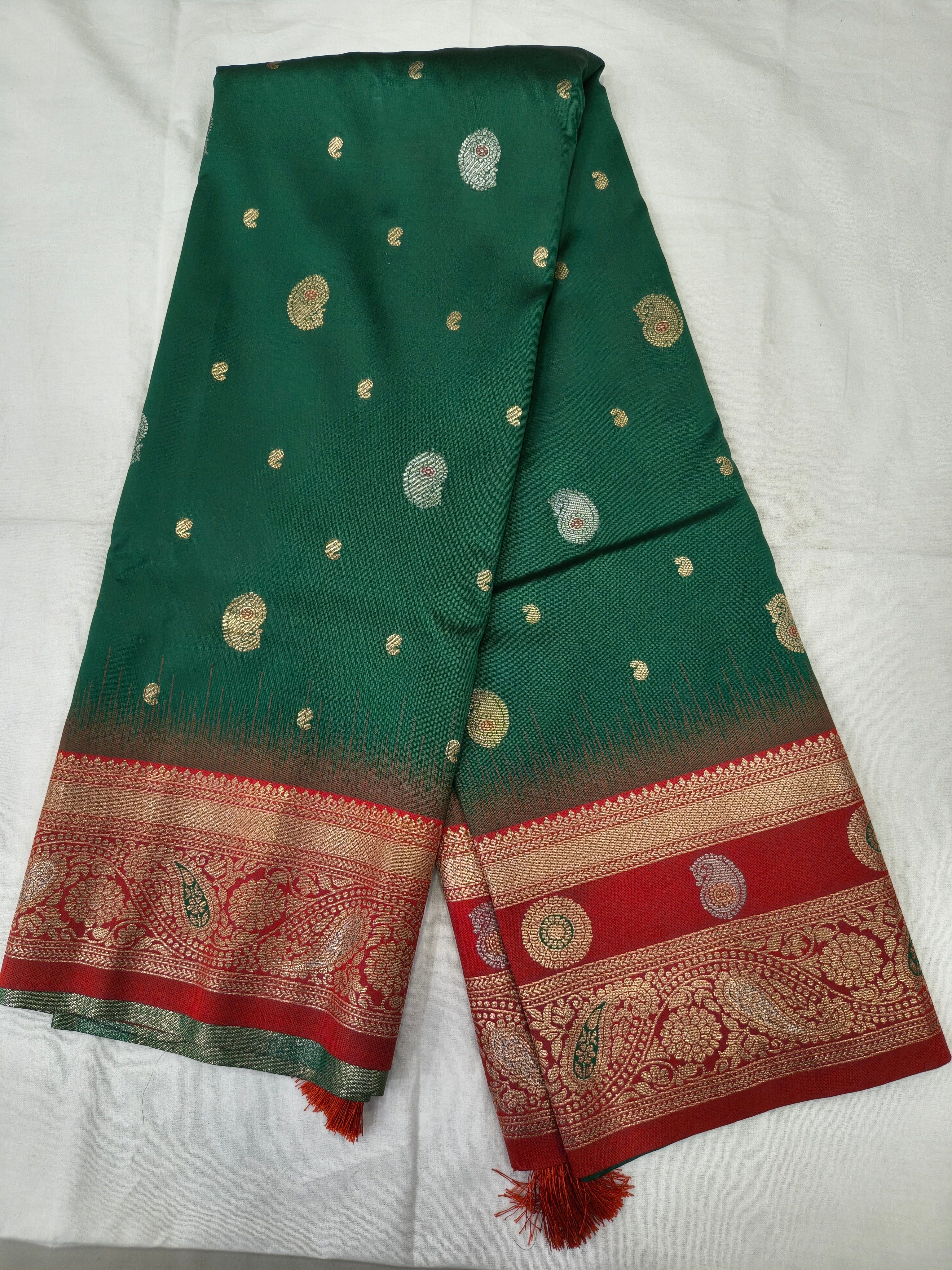 Teal green silk saree folded flat with small gold motifs and red patterned border