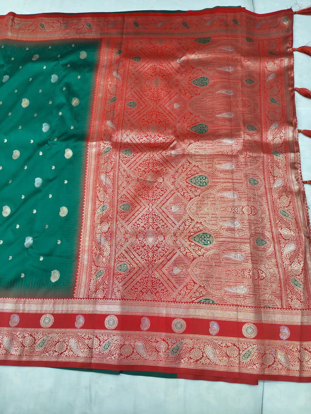 Banaras silk saree close-up: teal section with gold dots and red ornate central panel