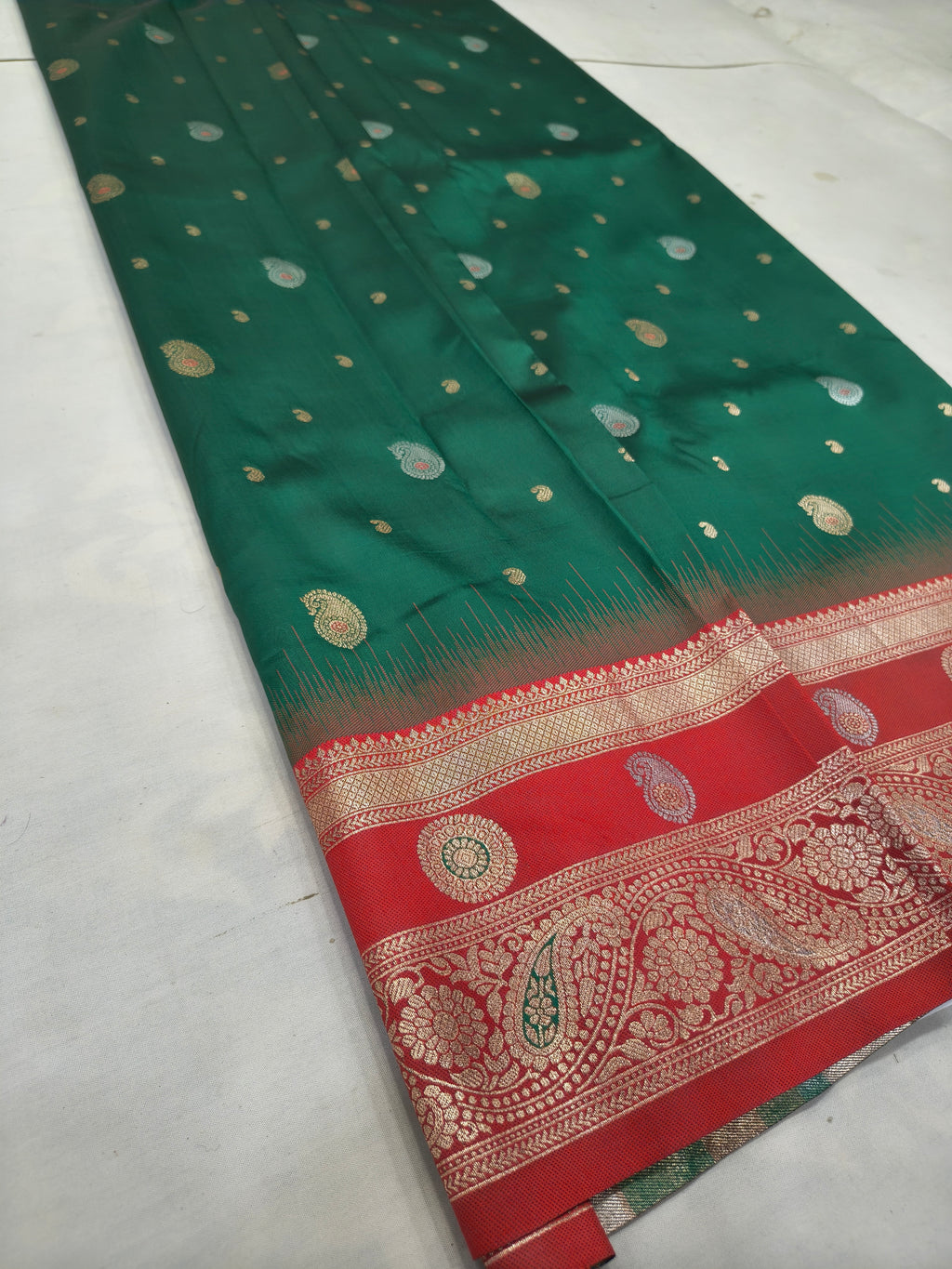 Teal green silk saree with scattered gold motifs and red border with paisley patterns