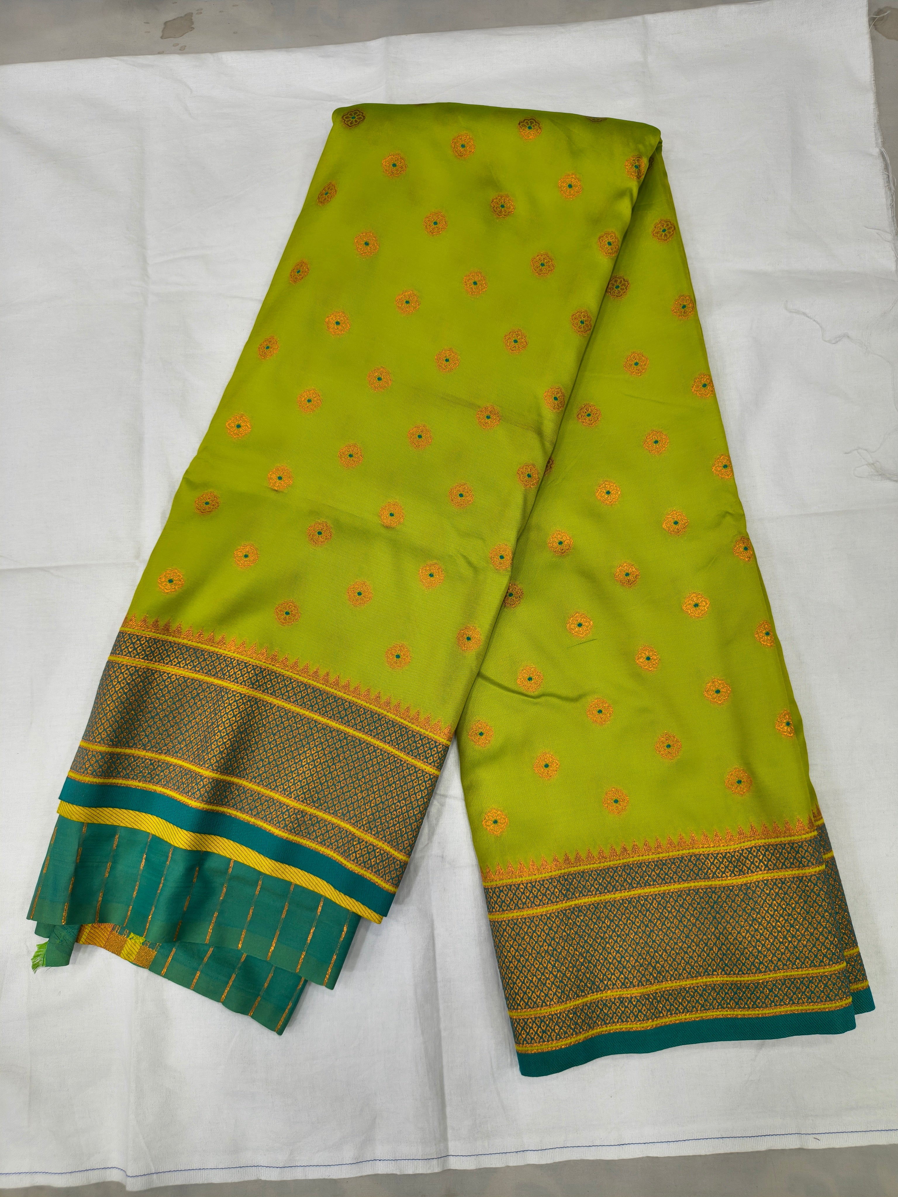 Neon yellow silk saree with red-gold motifs and navy-blue border, teal pallu